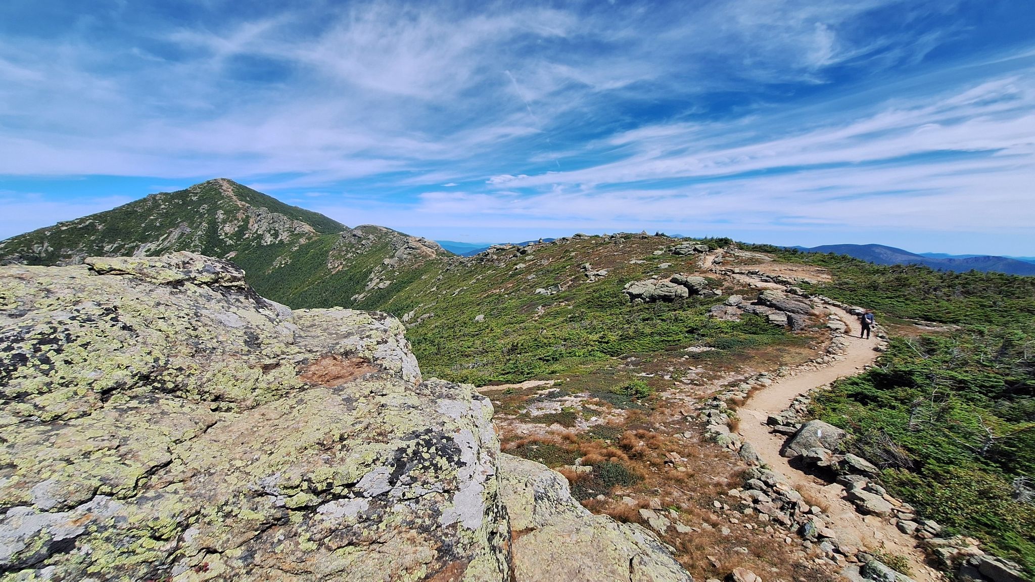 Winding rocky trail on a mountain ridge under a blue sky with wispy clouds. - Franconia Ridge Loop
