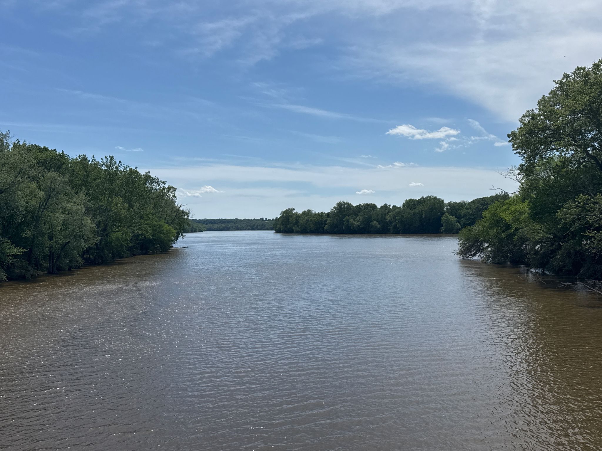 Wide river with wooded banks under a bright, partly cloudy sky. - Chesapeake and Ohio Canal Trail