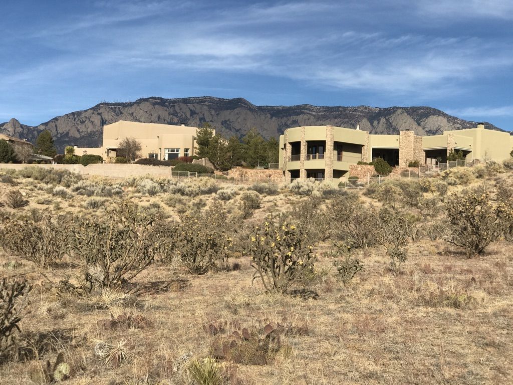 Modern buildings in a dry desert landscape with a mountain backdrop. - Bear Canyon Trailhead loop from High Desert