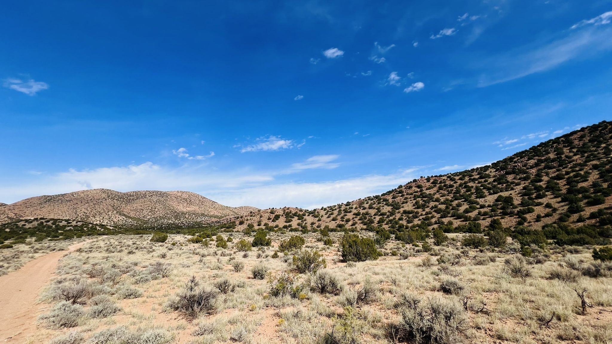 Sunny desert landscape with a dirt path leading towards distant hills. - Joseph’s Mine Trail