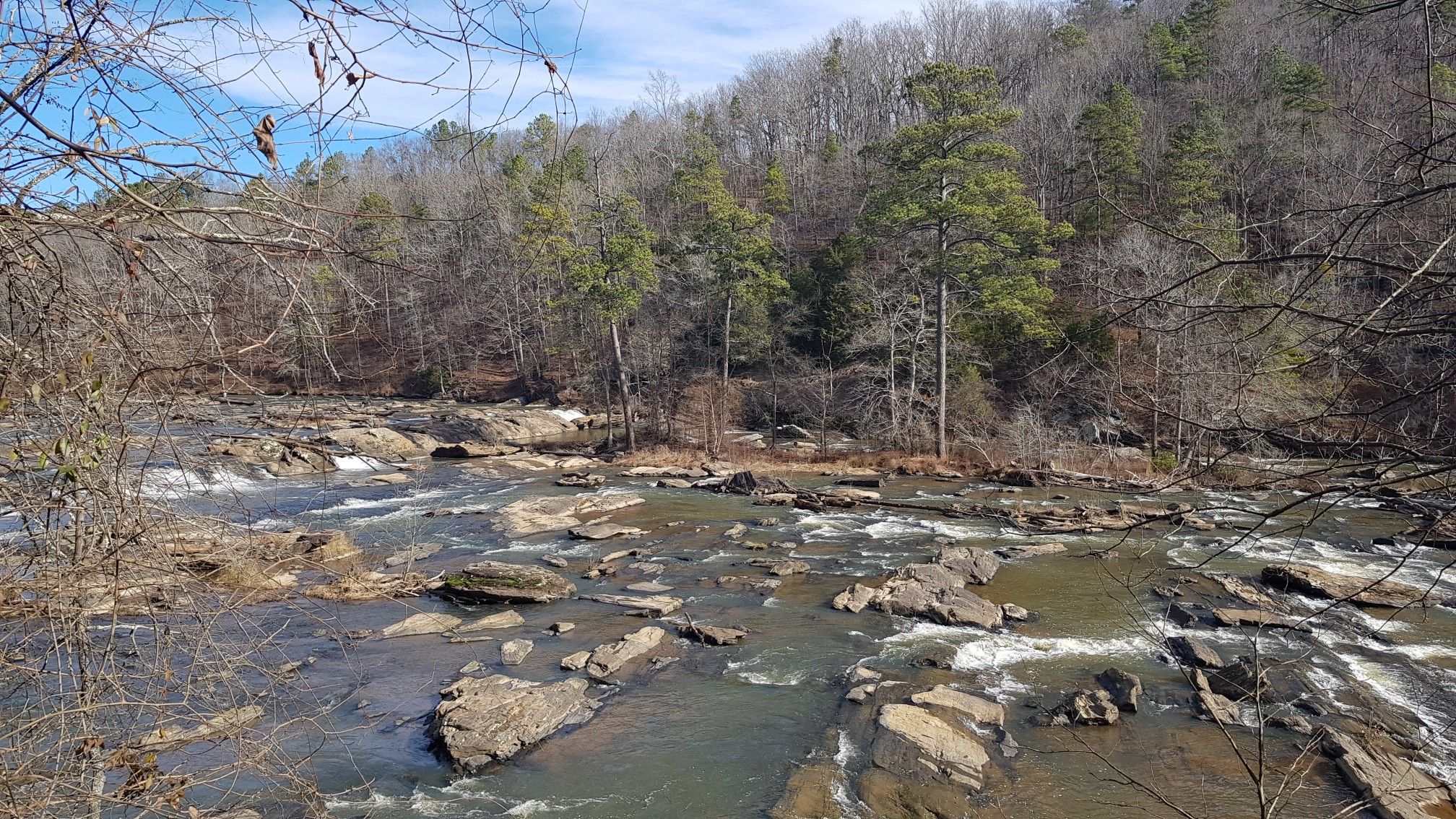 Rocky river rapids flow through a forest with bare and evergreen trees. - Sweetwater Creek Yellow, Red, and White Loop