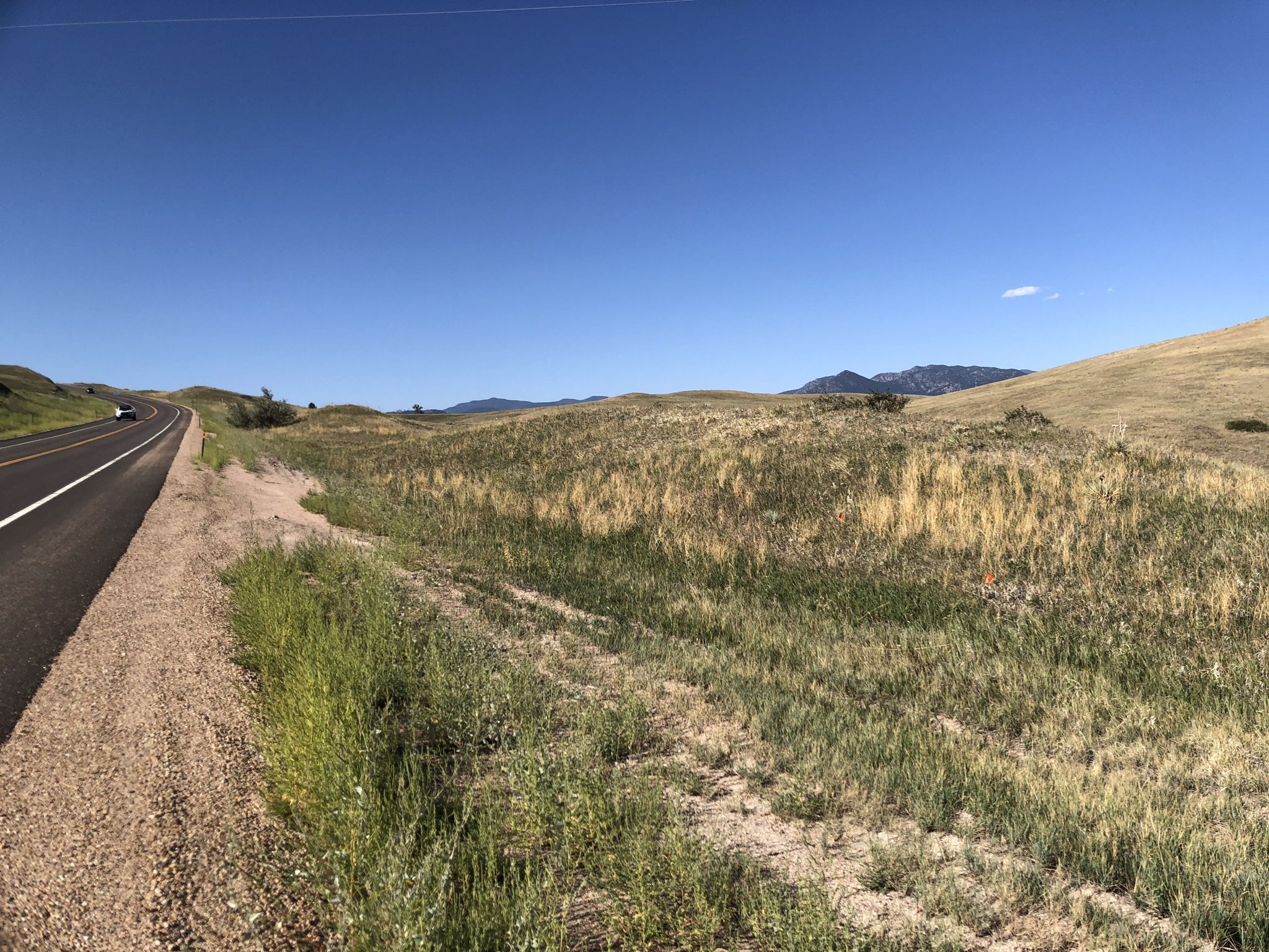 A long road next to dry, grassy hills under a clear blue sky. - Broomfield County High Point – Eldorado Market loop from Flatiron Crossing