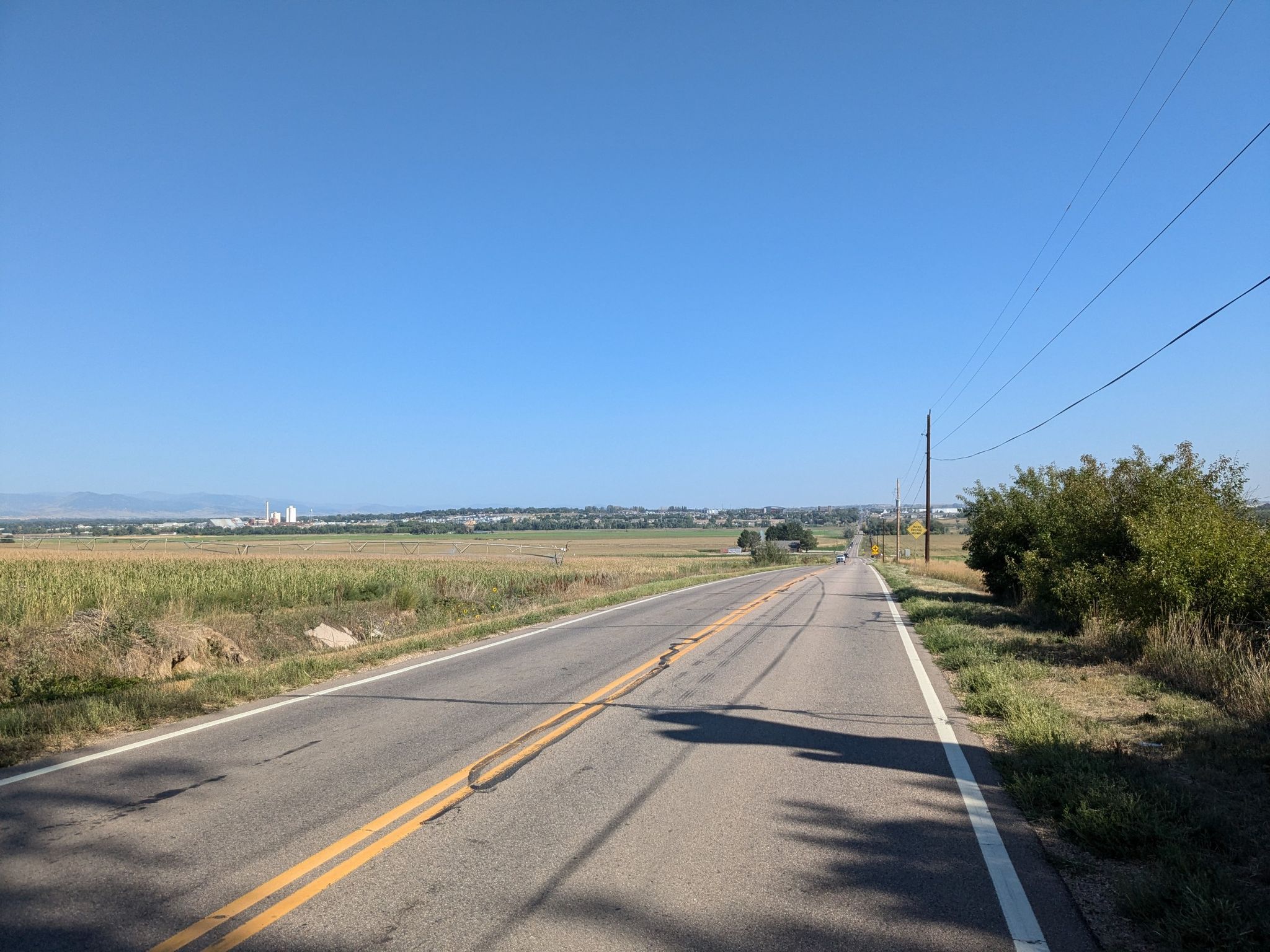 Empty road through flat fields under a clear blue sky on a sunny day. - Erie to Left Hand Creek Park loop via Countryside Bike Path