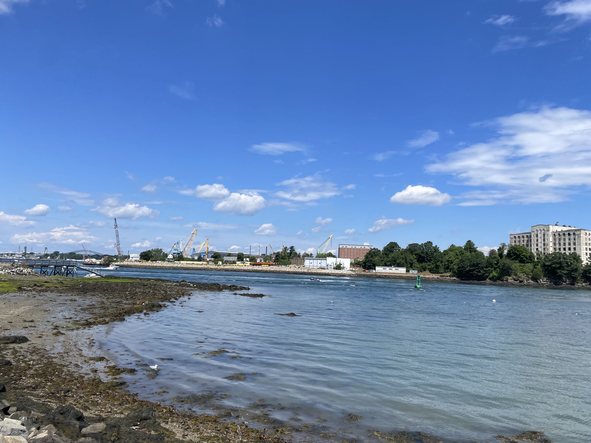 An industrial waterfront with cranes, calm water, and a bright blue sky. - New Castle – New Castle Park loop from Portsmouth