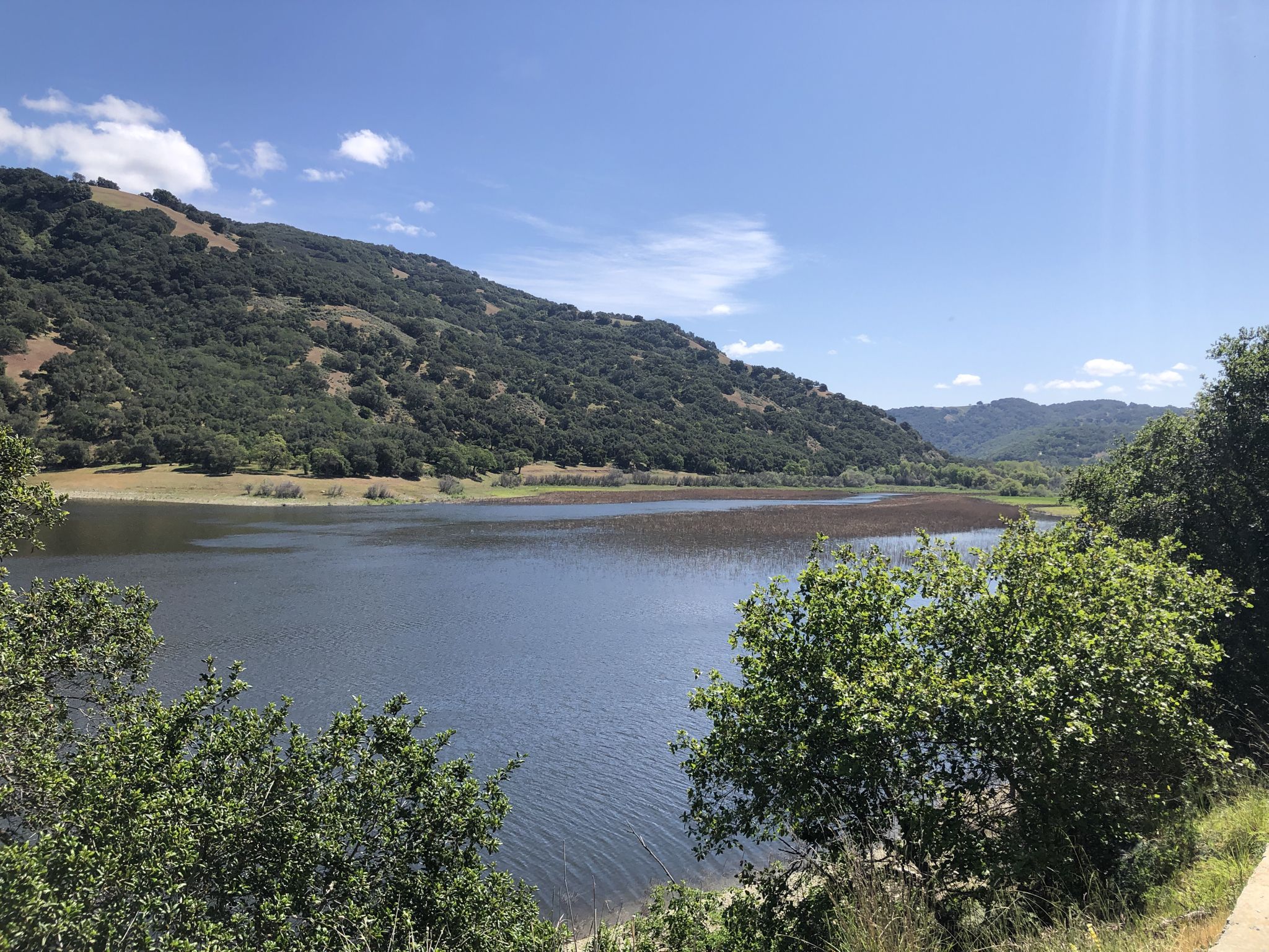 A serene lake surrounded by lush green hills under a bright blue sky. - Gaviota and Valley Oak Trail Loop