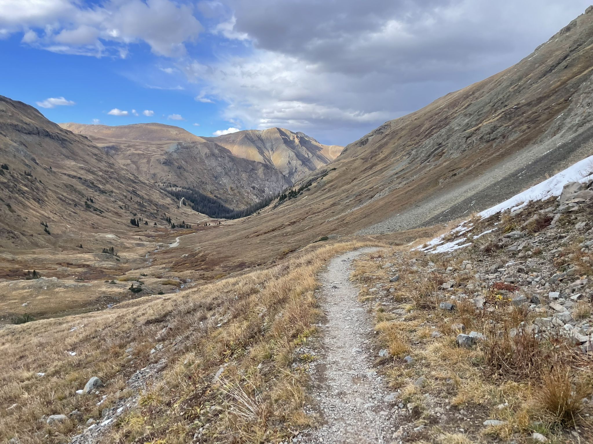 A winding trail through a dry mountain valley under a partly cloudy sky. - American Basin Trail