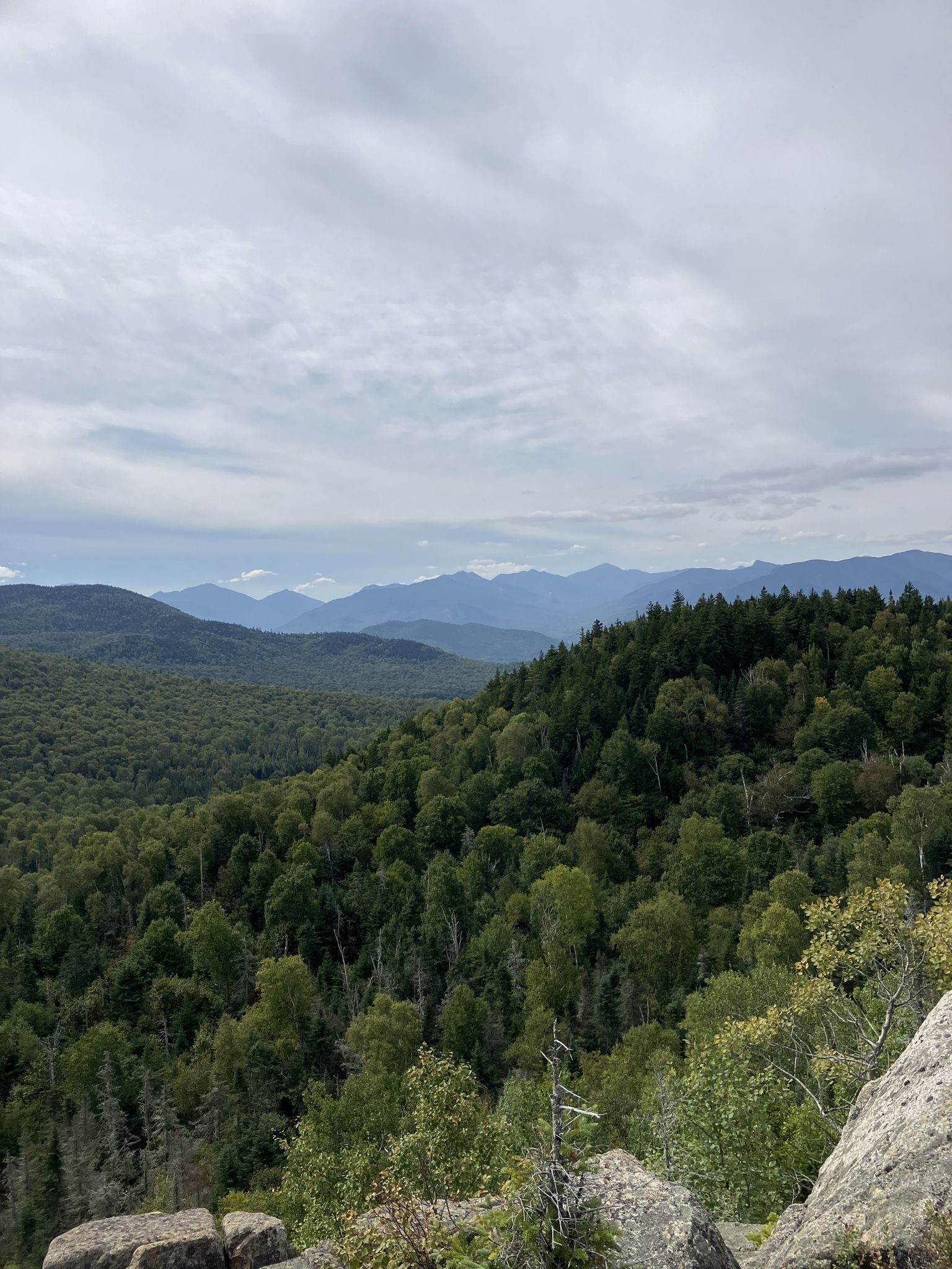 Overcast sky above vast forested mountains and rocky foreground. - Big Crow & Nun-Da-Ga-O Ridge loop