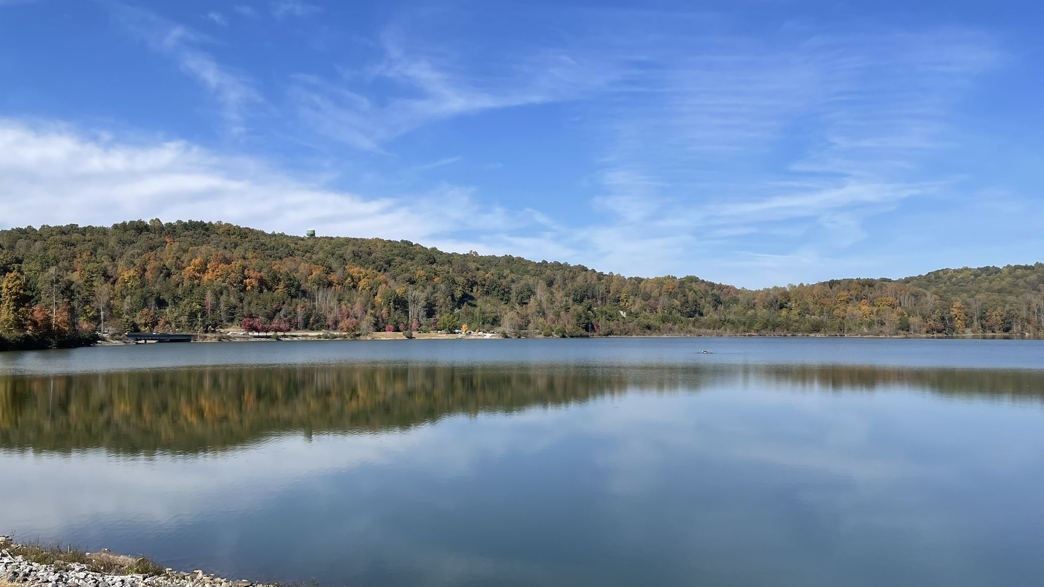 Calm lake reflecting autumn-colored forested hills under a bright blue sky. - Lake Zwerner Loop