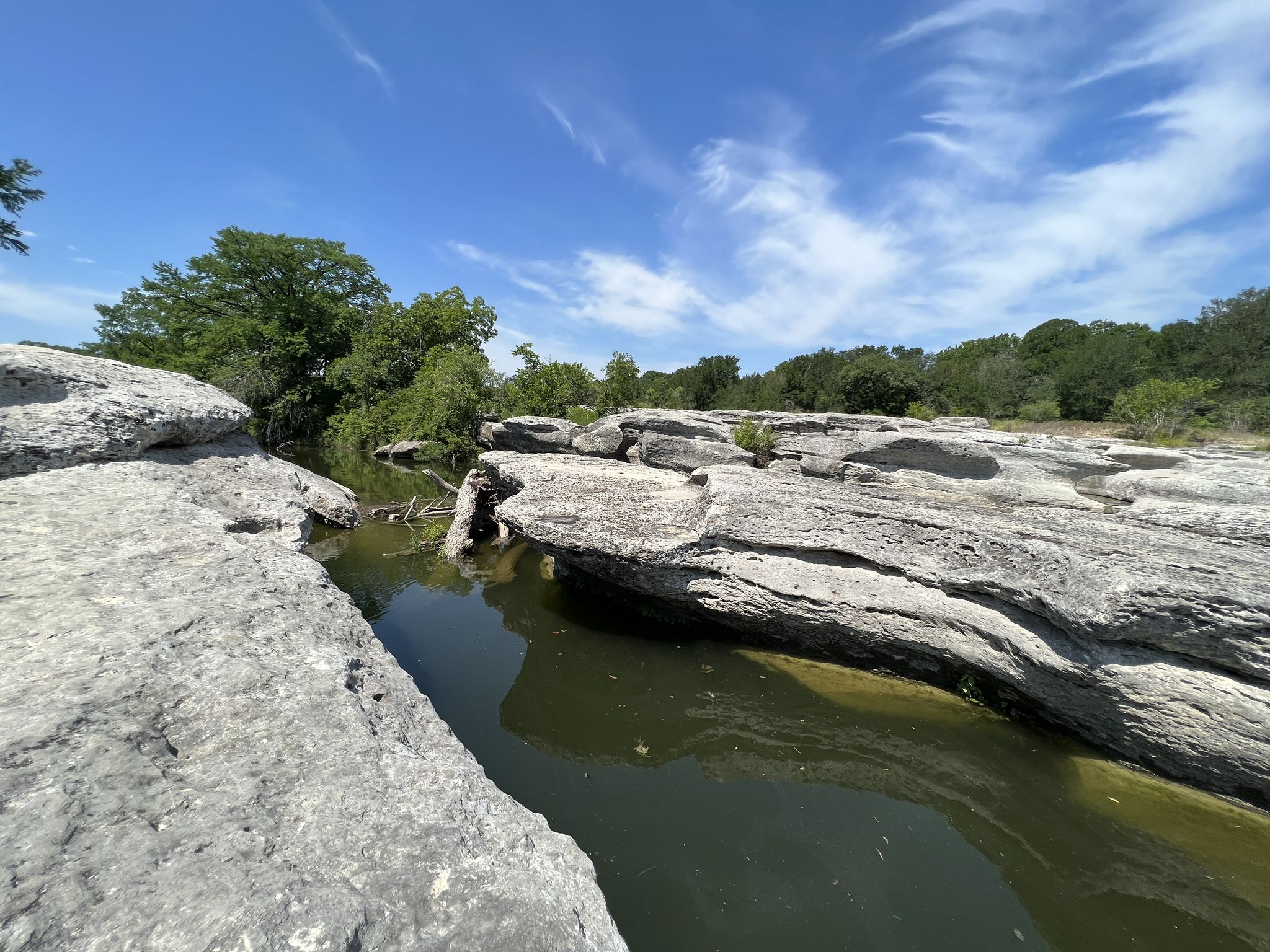 Rocky creek with clear water under a bright blue sky and green trees. - Lower Falls and Homestead Loop Trail