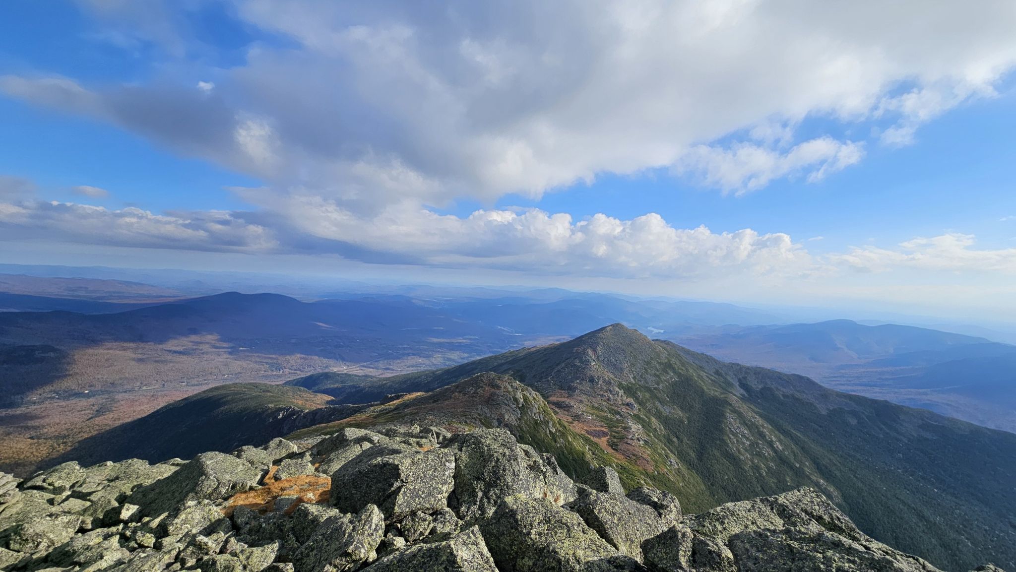 Rocky mountain peak under a bright, partly cloudy sky with distant valleys. - Lowe's Path
