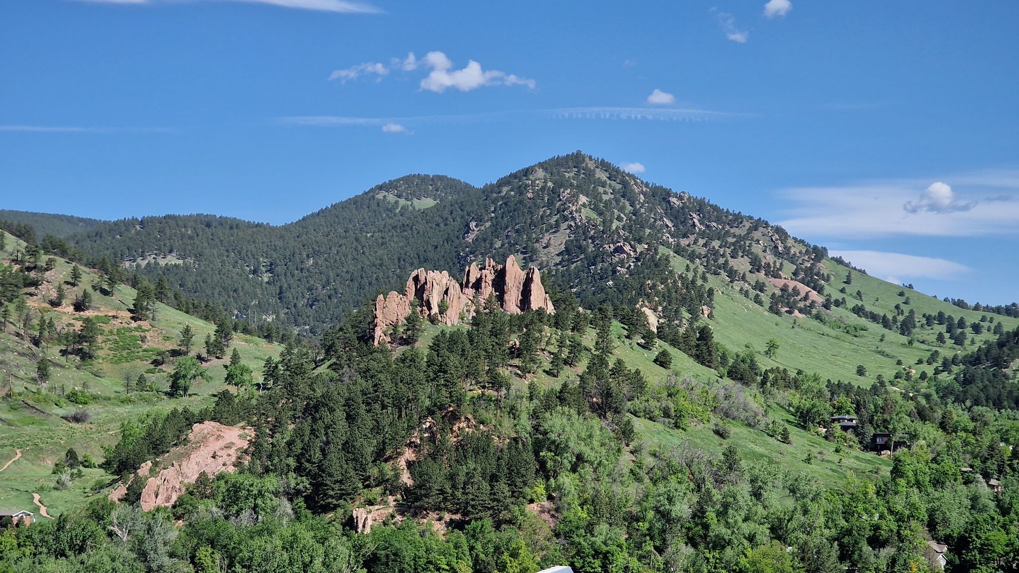 Lush green mountains with prominent rocky formations under a bright blue sky. - Viewpoint Trail