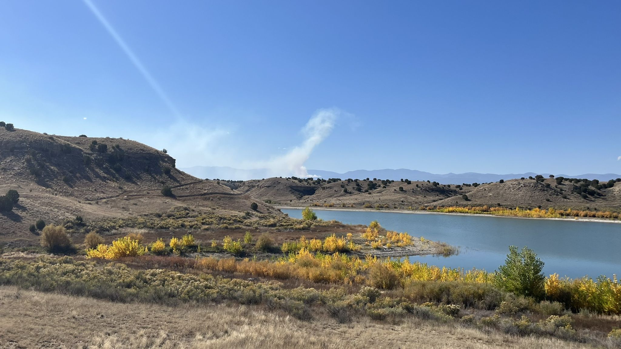 Sunny view of a lake bordered by arid hills and yellow trees. - Outer and Inner Limits Loop