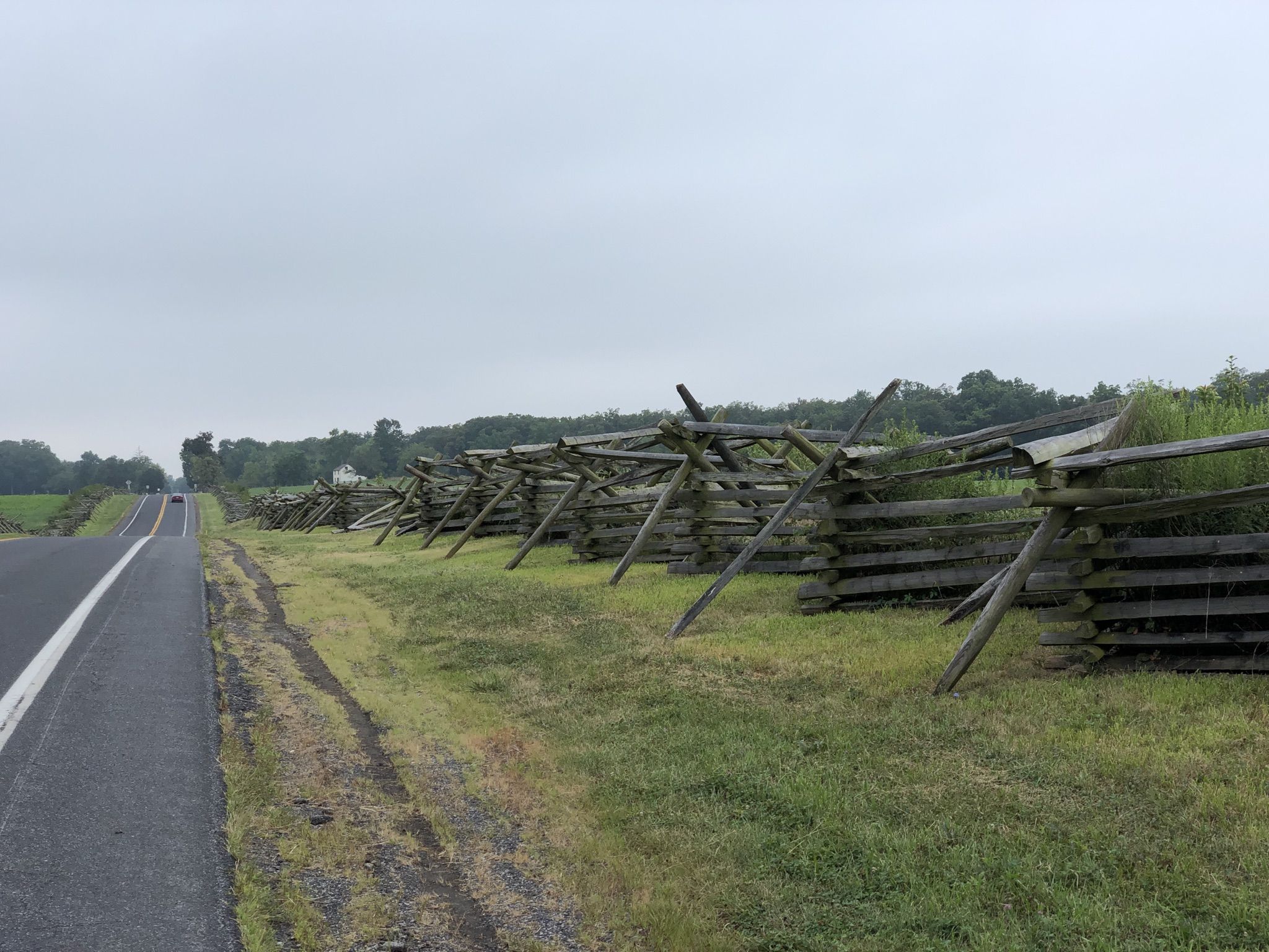 A long split rail fence runs alongside a road under an overcast sky. - BicyclePA Route J2: Gettysburg National Park Loop