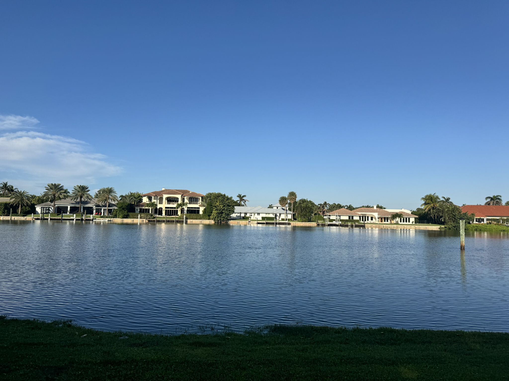 Calm water reflecting large houses and palm trees under a clear blue sky. - Ocean Ridge Natural Reserve – Lake Worth Beach Park with pier loop from Lake Worth