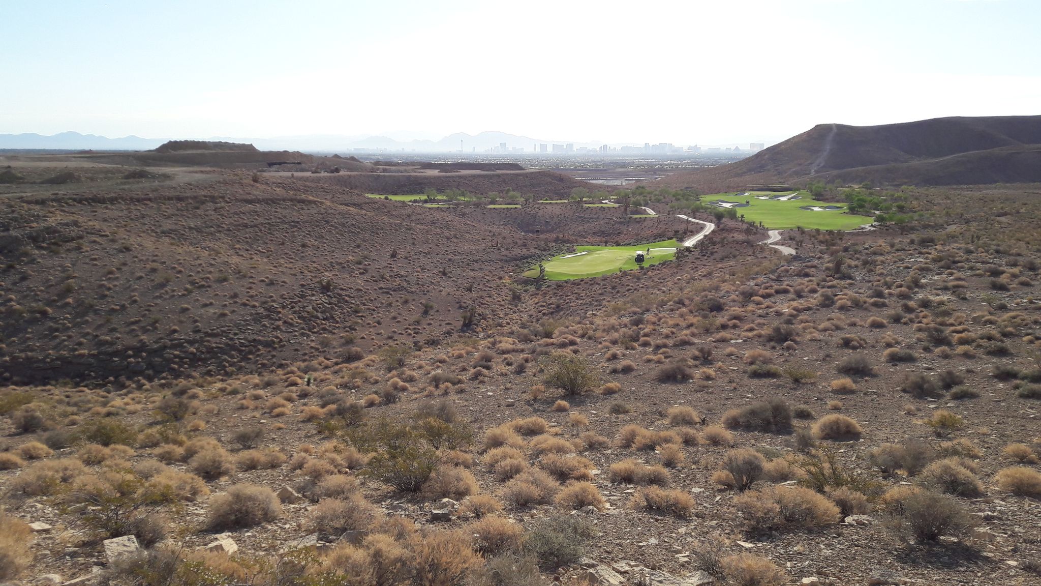 Elevated view of a desert golf course with green fairways amidst arid hills. - Bears Best Trailhead loop from Summerlin South