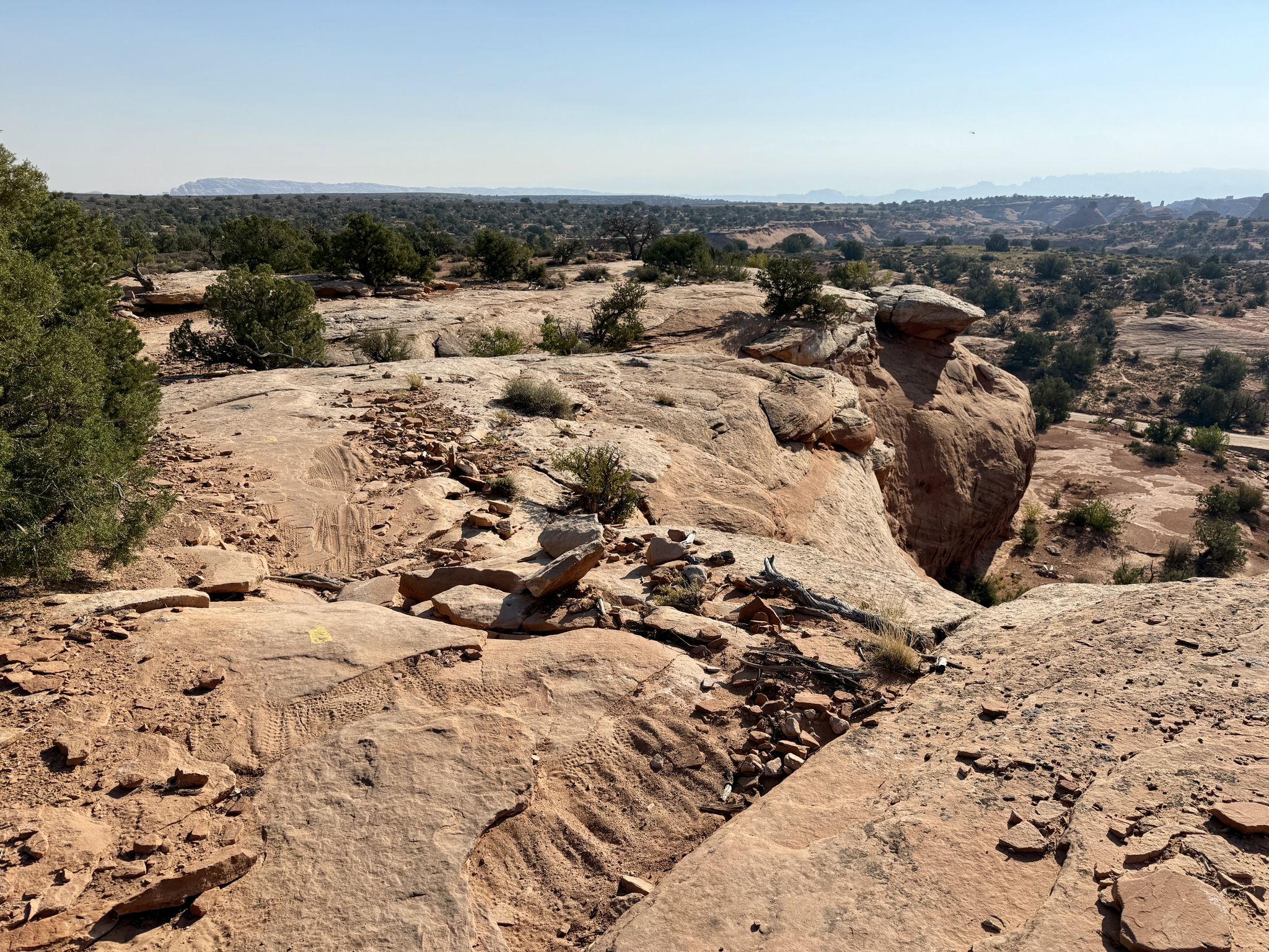 Expansive desert landscape with large rock formations and sparse green bushes under clear sky. - Mag7 to Portal – Best of Moab MTB Trails
