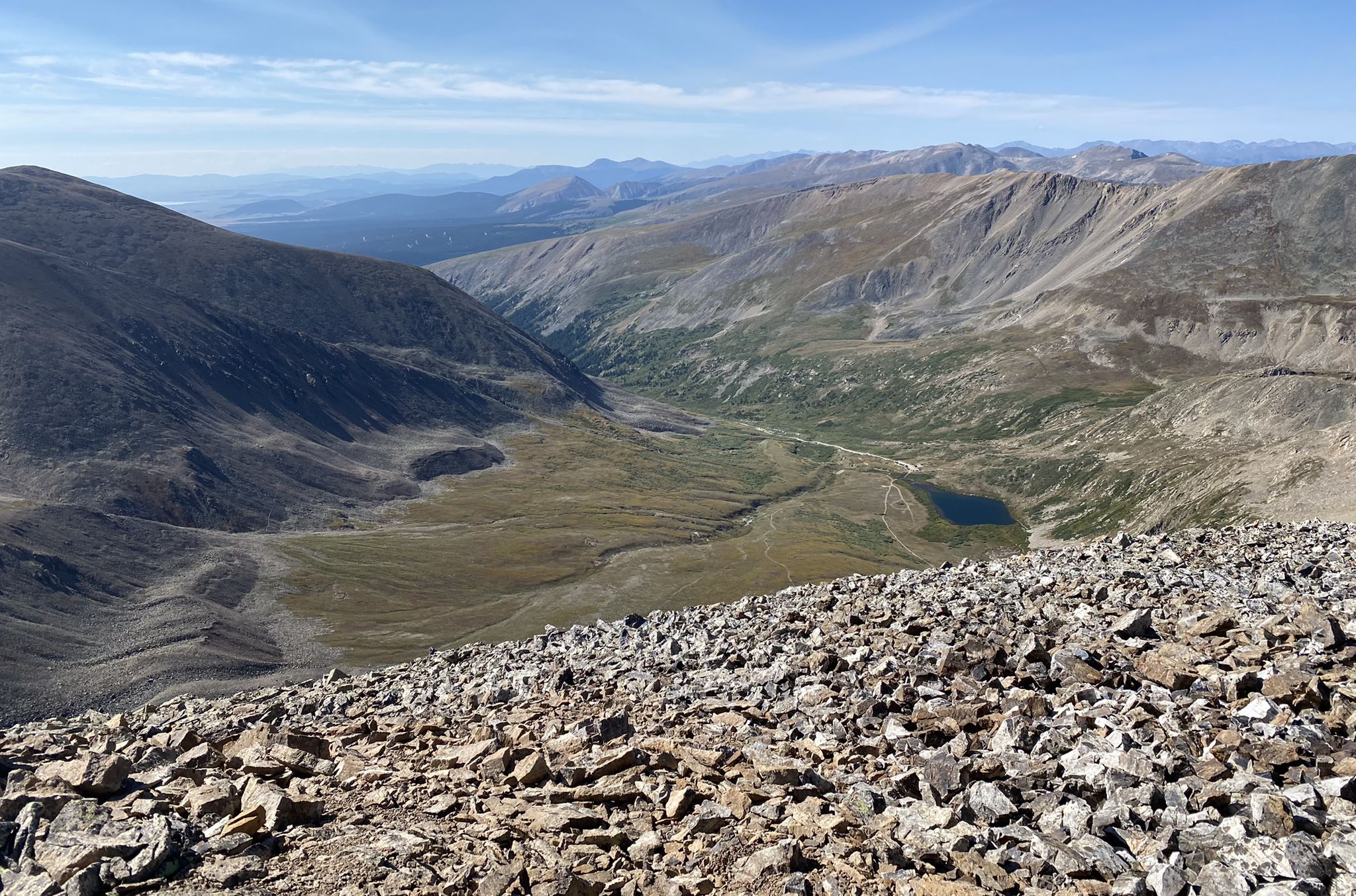 Wide valley with green and brown slopes, a small lake, under clear sky. - The DeCaLiBron (Democrat, Cameron, Lincoln, & Bross) Loop