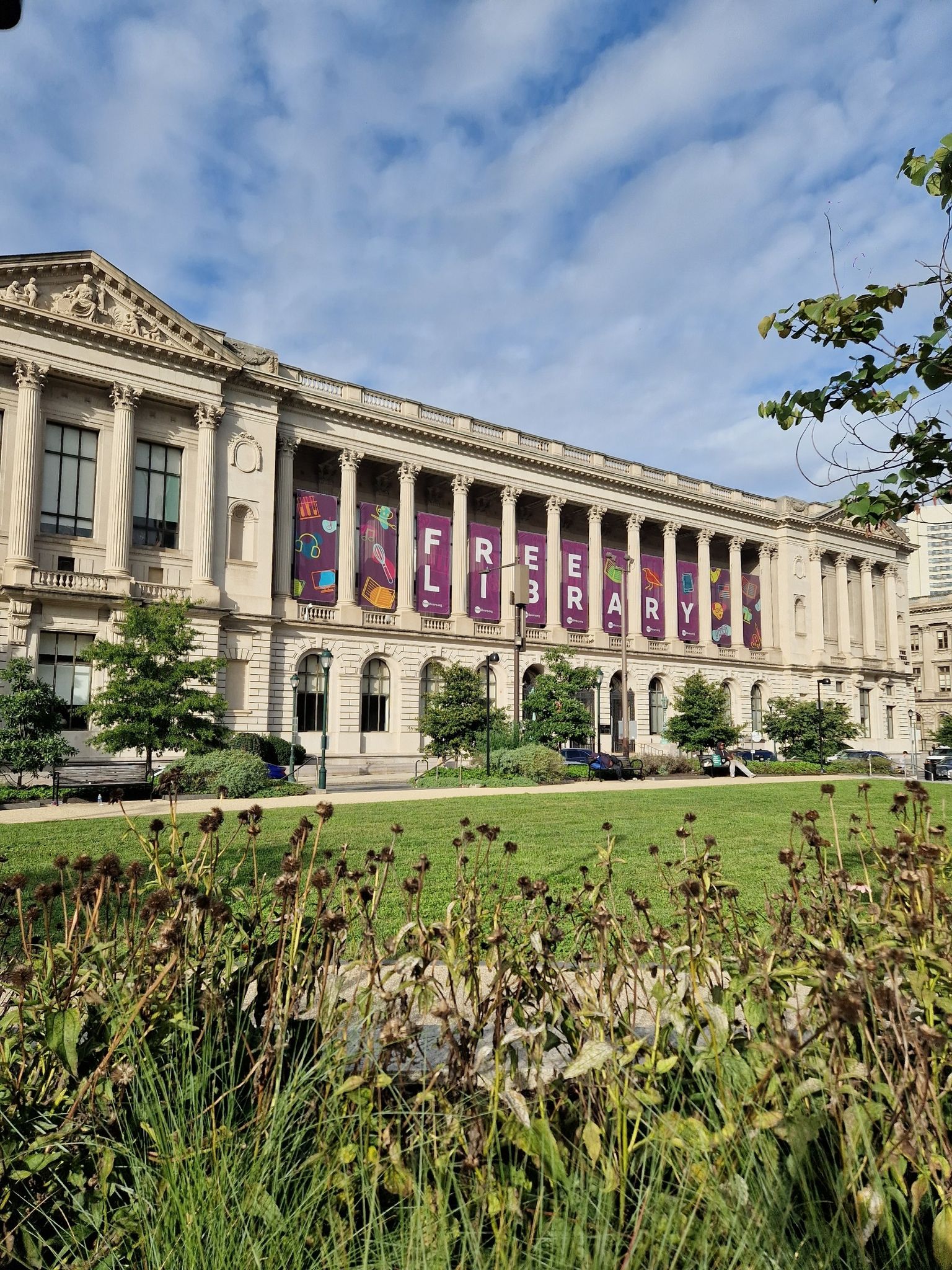 Grand classical building with banners on columns, green lawn in foreground. - Rocky Statue – LOVE Sculpture, Love Park loop from Philadelphia