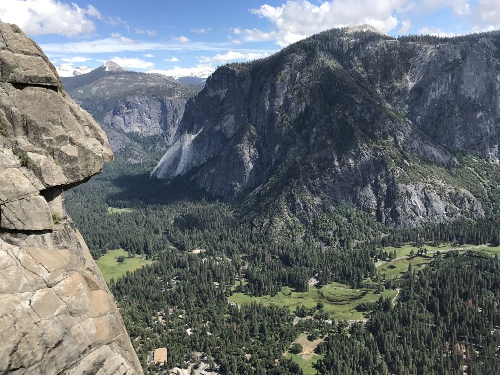 High-angle view of a lush green valley surrounded by towering mountains. - Yosemite Creek Trail