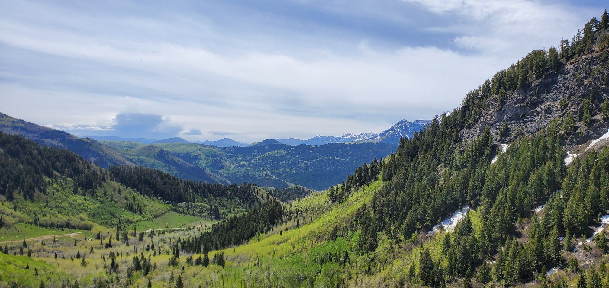 Expansive mountain valley with lush green forests under a partly cloudy sky. - Silver Lake Trail