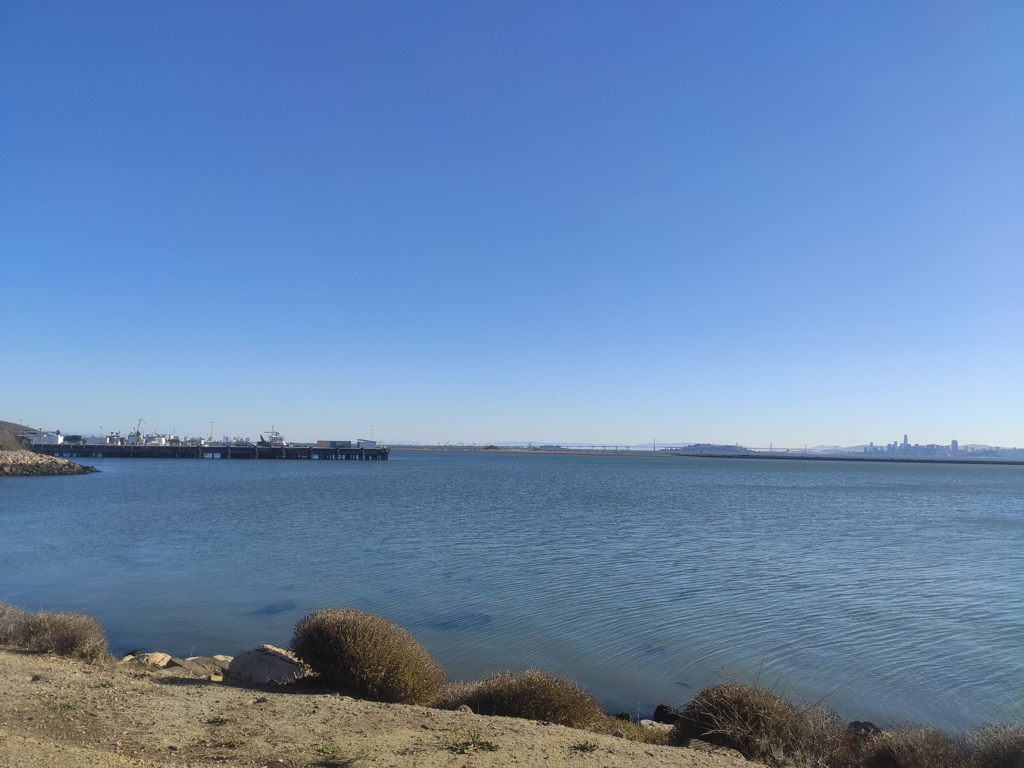 Wide view of calm blue water, distant pier, and clear sky. - Roadbike loop from Rosie the Riveter/World War II Home Front National Historical Park