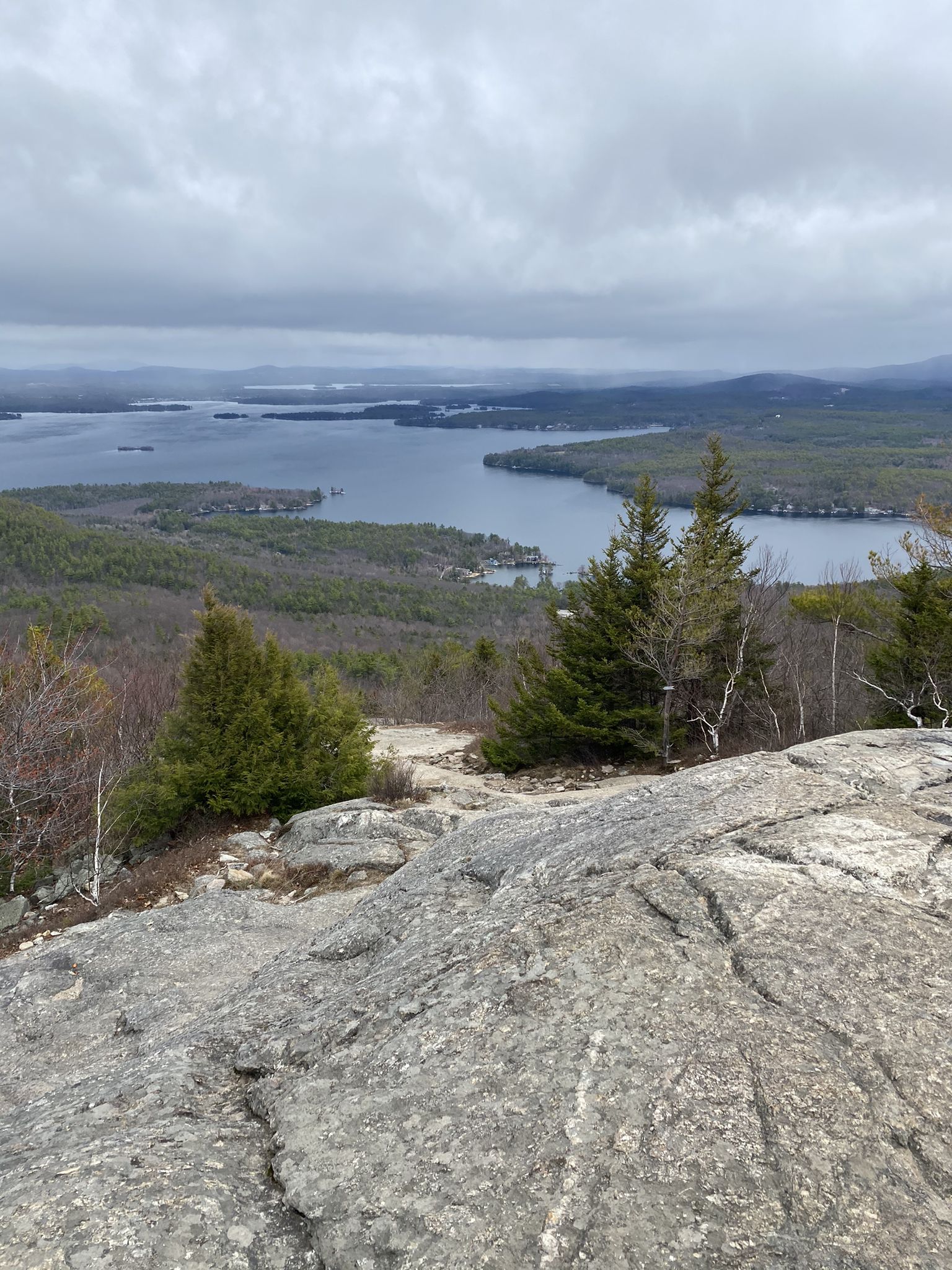 Rocky mountain summit overlooking a vast lake and green forests under cloudy skies. - Mount Major Trail