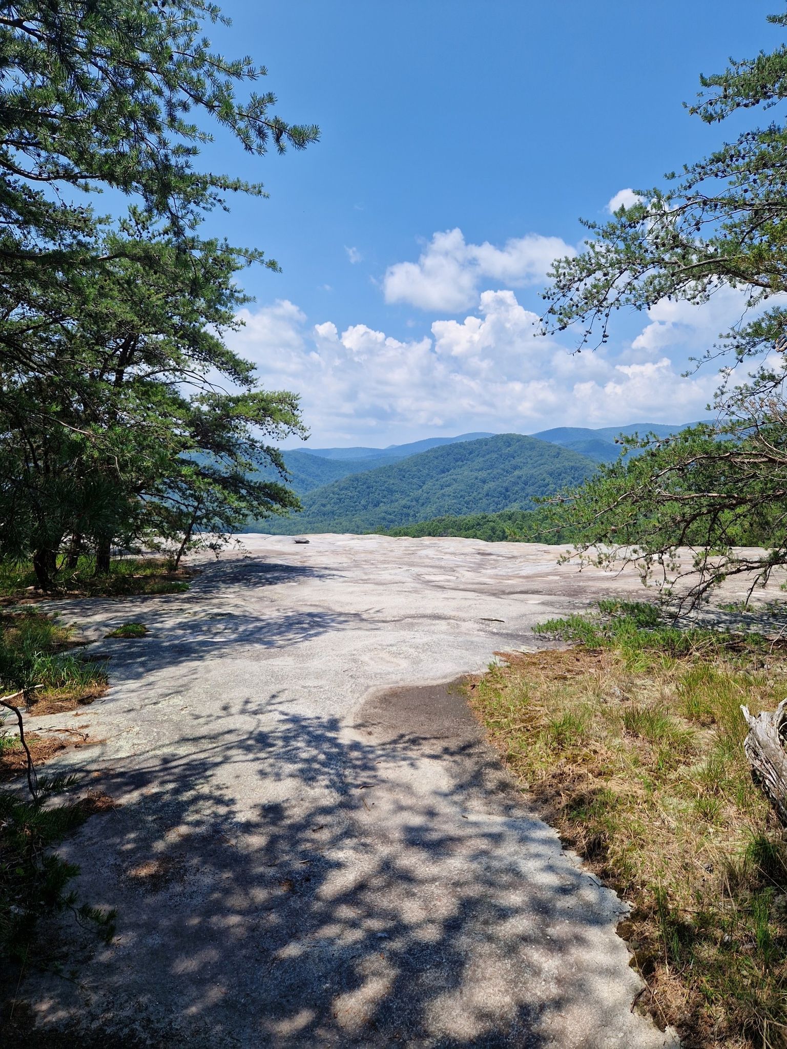 Sunny view from a large rock outcrop towards distant forested mountains. - Historic Hutchinson Homestead – Wolf Rock loop from Stone Mountain State Park