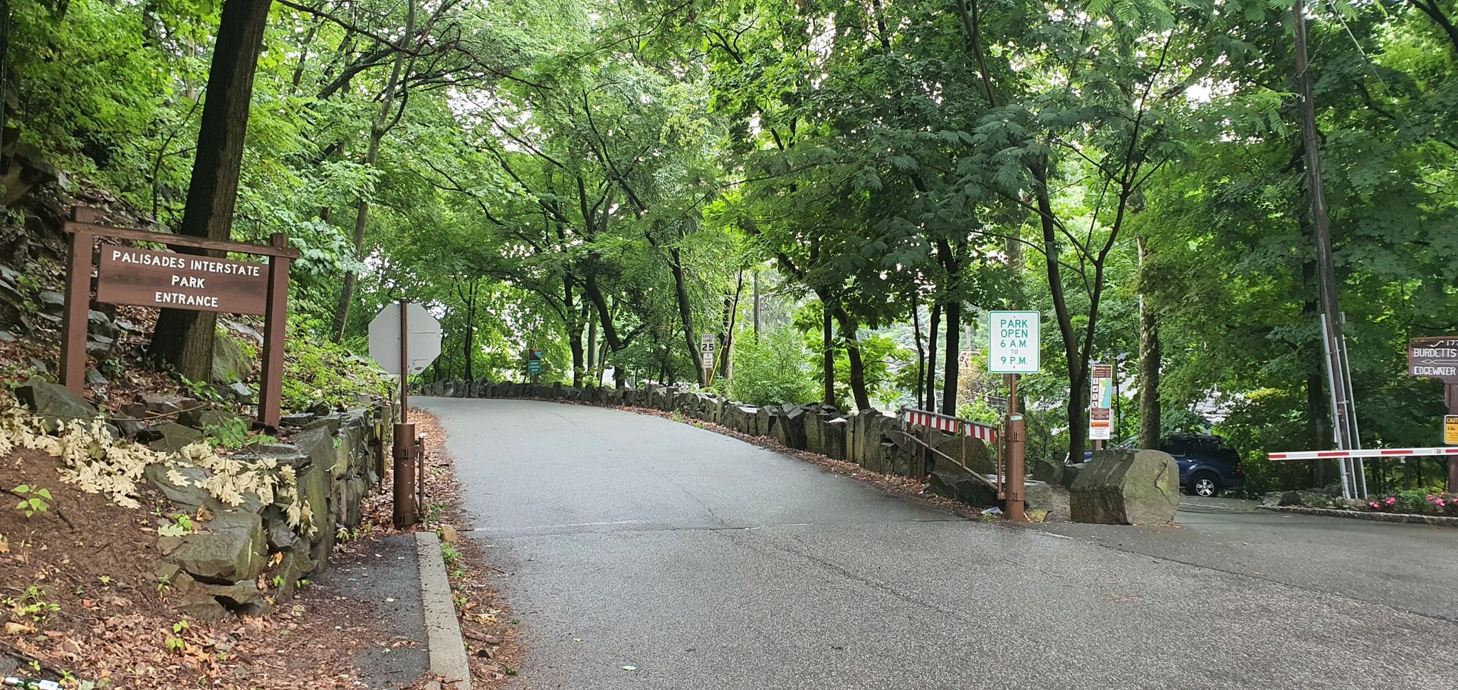 Park entrance sign and gate on a paved road surrounded by green trees. - Port Imperial Waterfront – River Road to GWB Climb loop from 9th Street–Congress Street