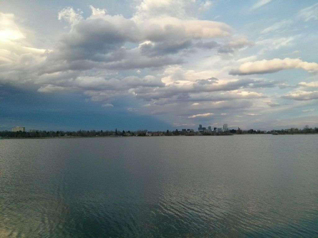 Wide lake under a cloudy sky, with a distant city skyline. - Sloan's Lake Park loop from Edgewater