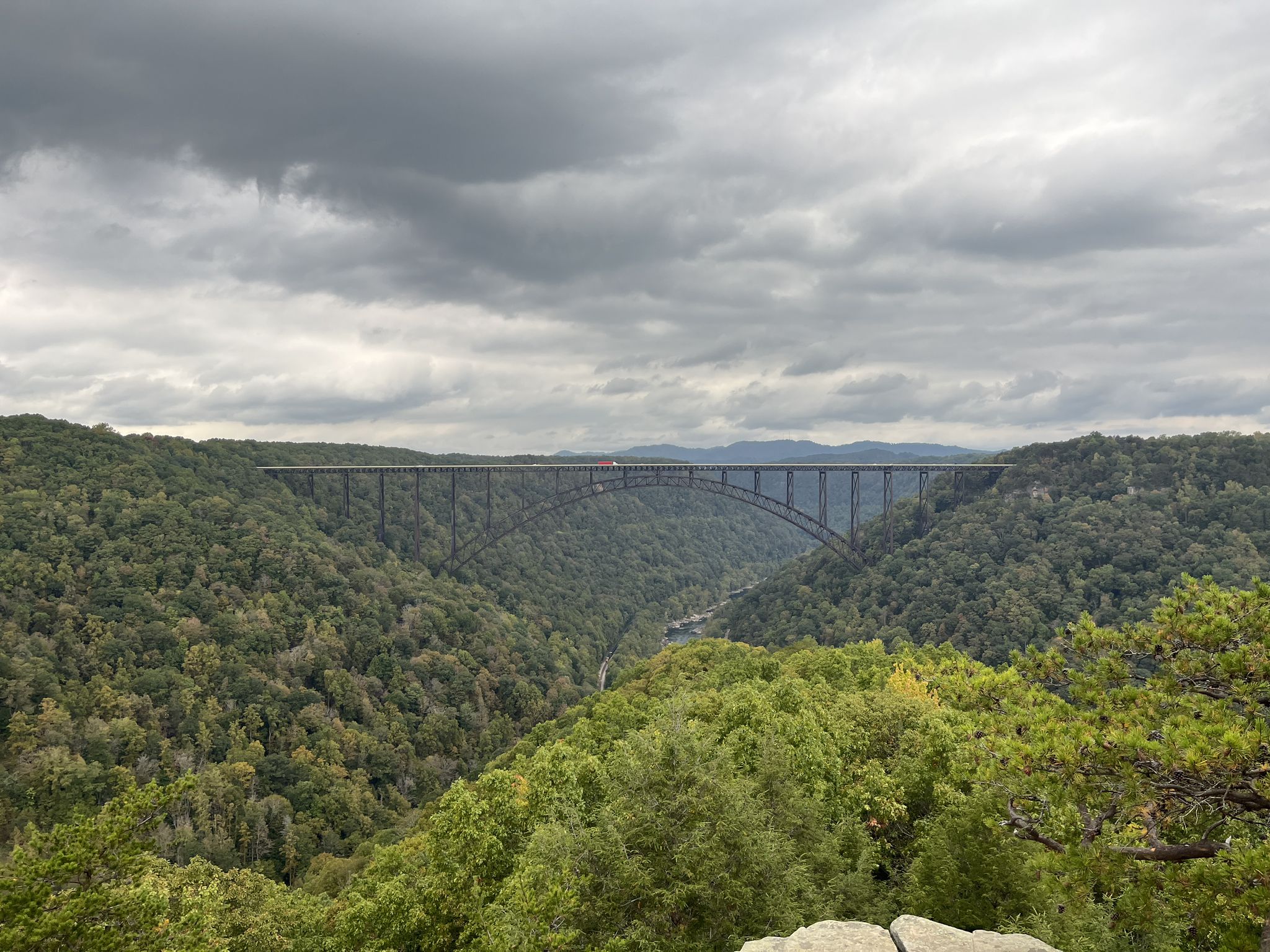 A large arch bridge spans a deep, forested gorge under a cloudy sky. - Long Point via Fayetteville Trail
