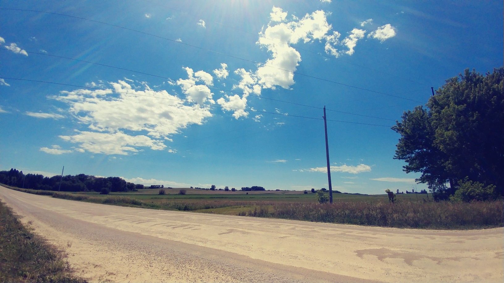 Wide dirt road through open fields under a bright, sunny, blue sky. - Douglas State Trail loop from Hyvee West Circle