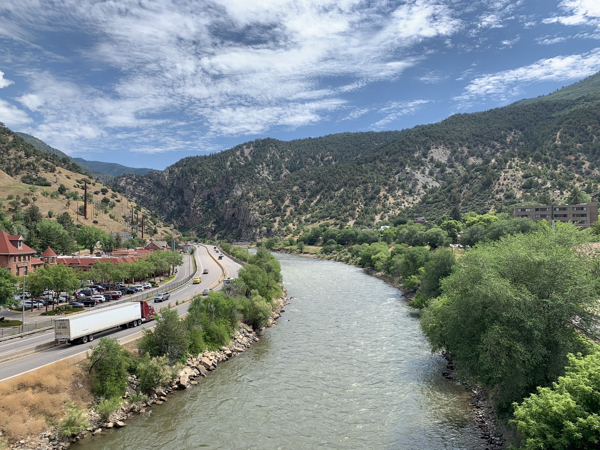 River next to a highway with cars and a truck, surrounded by mountains and trees. - Glenwood Springs – Scenic Landscape Murals loop from Glenwood Springs
