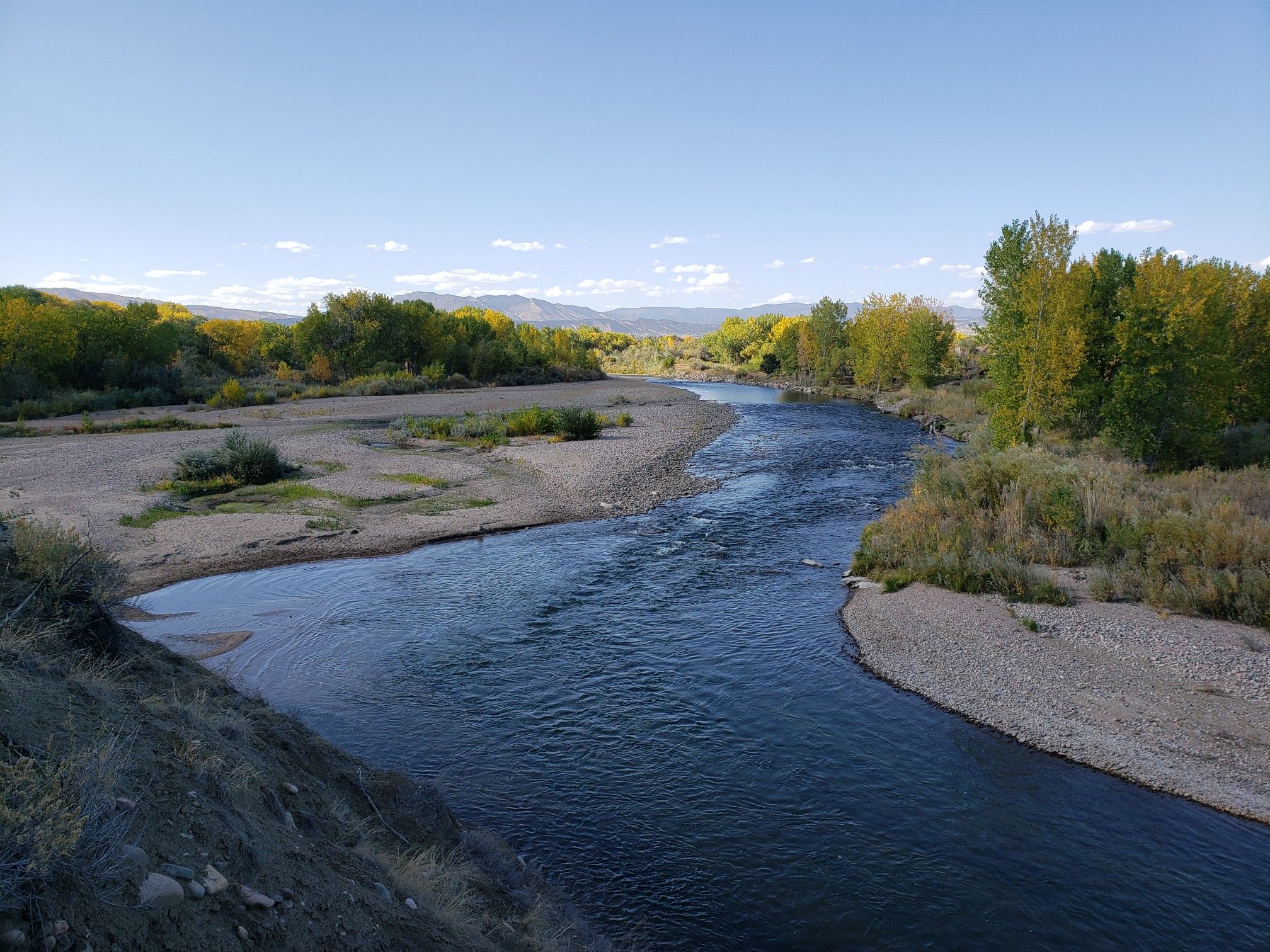Scenic river flowing through a wide valley with fall foliage under a blue sky. - Arkansas River Trail – Arkansas River Trail loop from Brookside