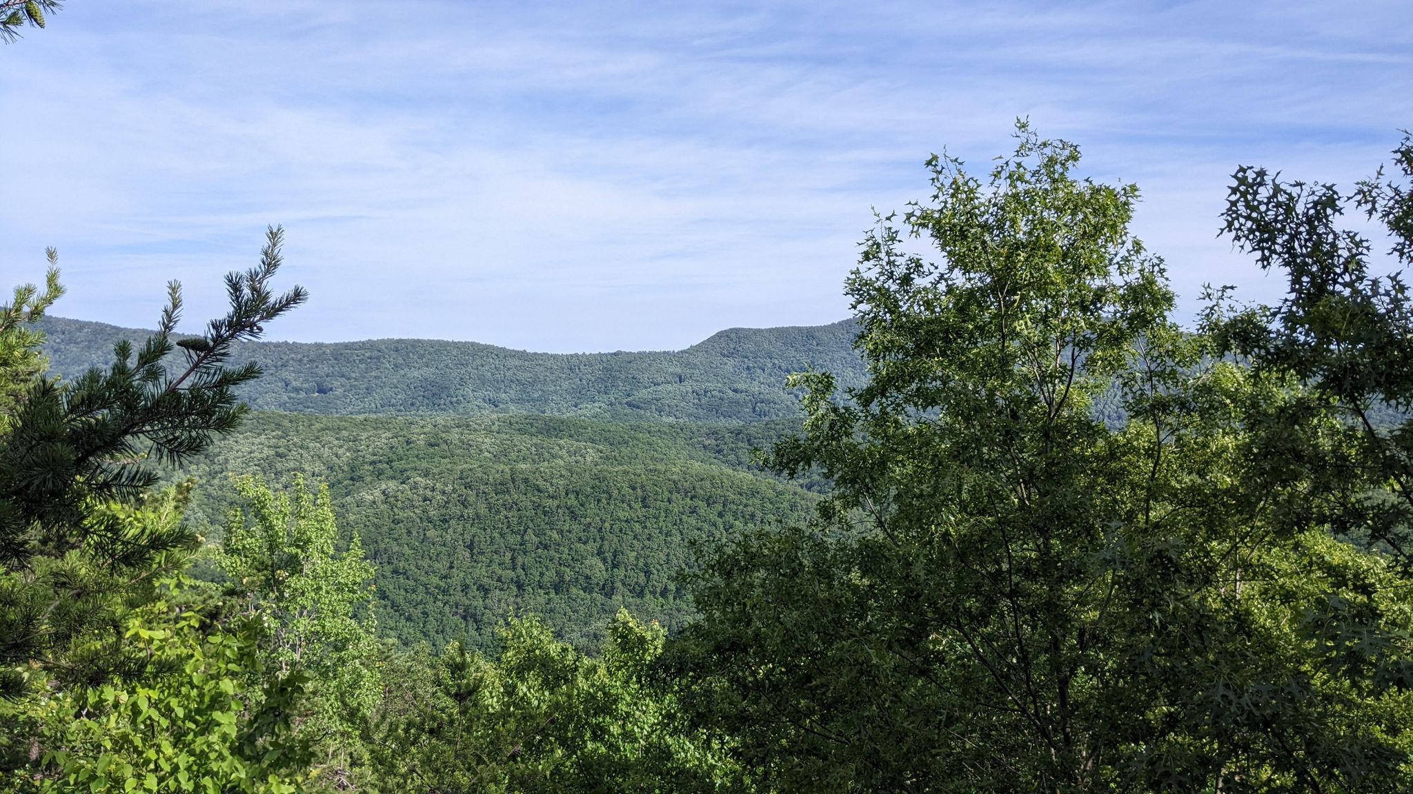 Expansive green forested mountains under a partly cloudy sky, viewed through trees. - Slacks Overlook Trail loop from South River Number 27 Dam