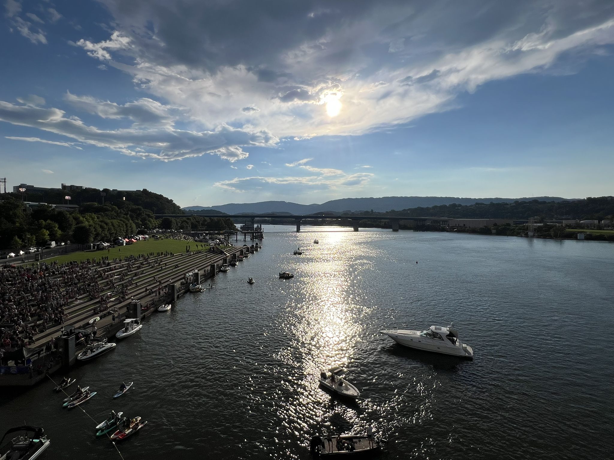 Wide river with boats, distant bridge, and a crowd on the sunny shore. - Ross's Landing – New York State Monument loop from Northside Presbyterian Church