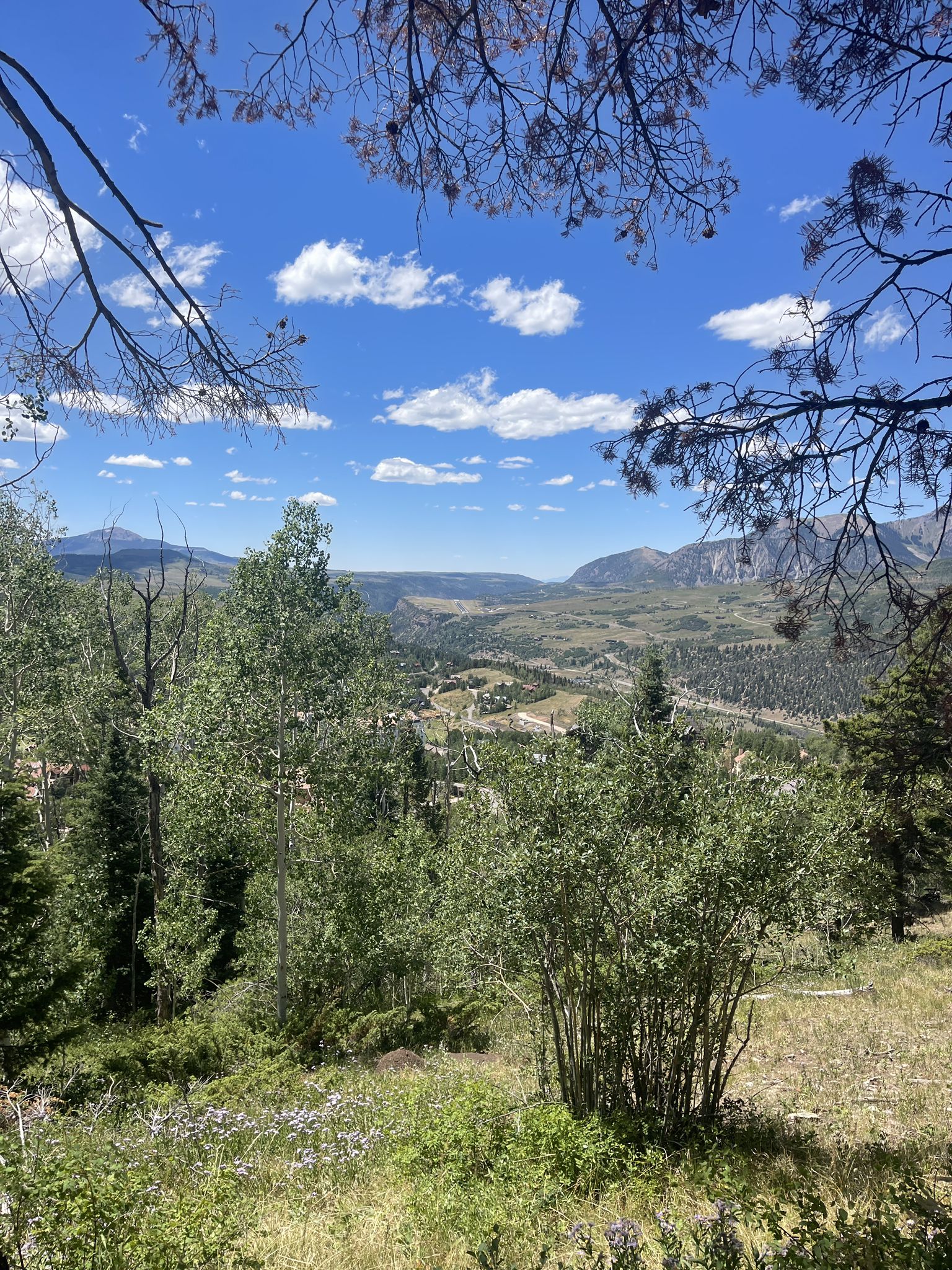 Panoramic view of a green mountain valley under a bright blue sky. - Ridge Trail