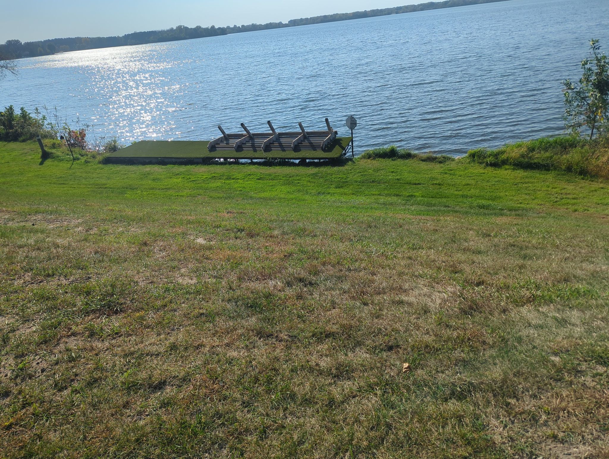 Green boat on a grassy bank beside a sparkling lake on a sunny day. - Sunken Lakeside Singletrack loop from Lino Lakes