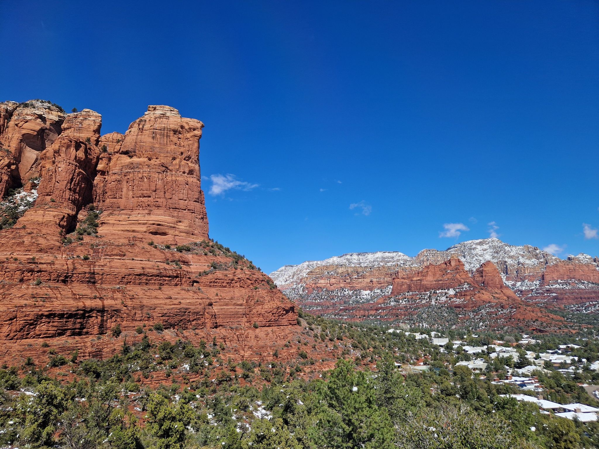 Large red rock formation with snow-capped mountains and a town in the distance. - Tea Cup #183