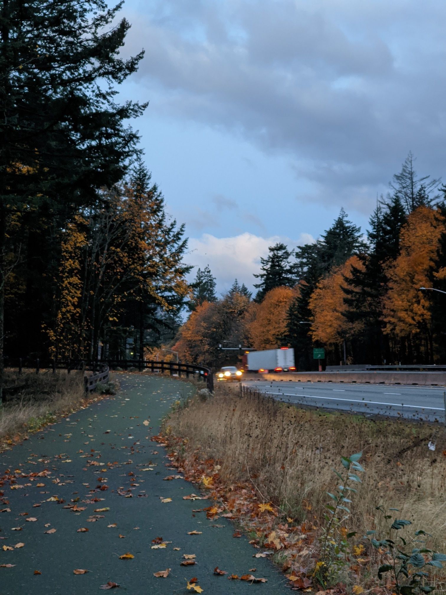 Paved path alongside a highway with autumn trees and vehicles at dusk. - Mt. Defiance Trailhead – Starvation Creek State Park loop from Wyeth State Recreation Area