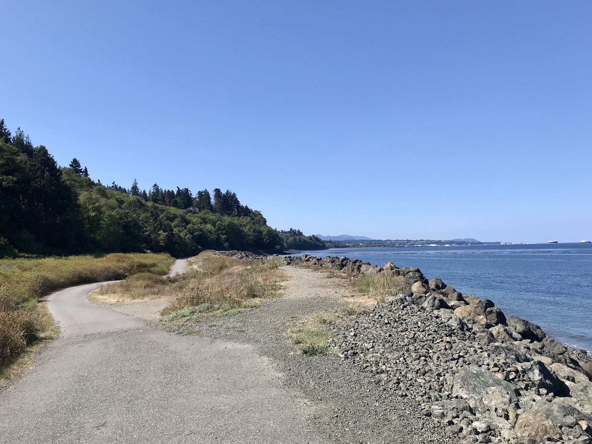 Paved path next to a rocky shore and calm water on a clear day. - Olympic Discovery Trail: Port Angeles Waterfront