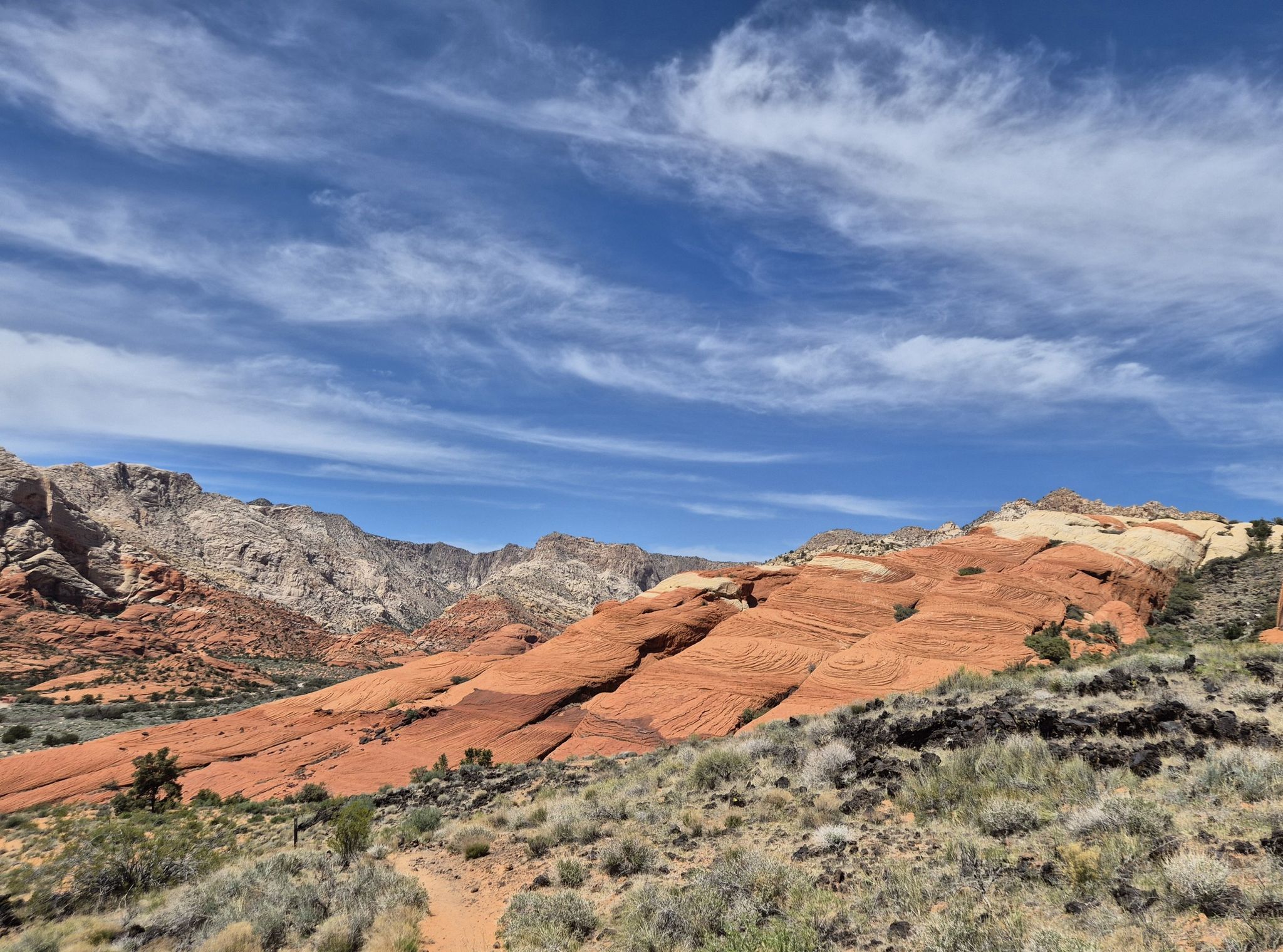 Red and white striped rock formations in a desert landscape under a blue sky. - Lava Flow Trail