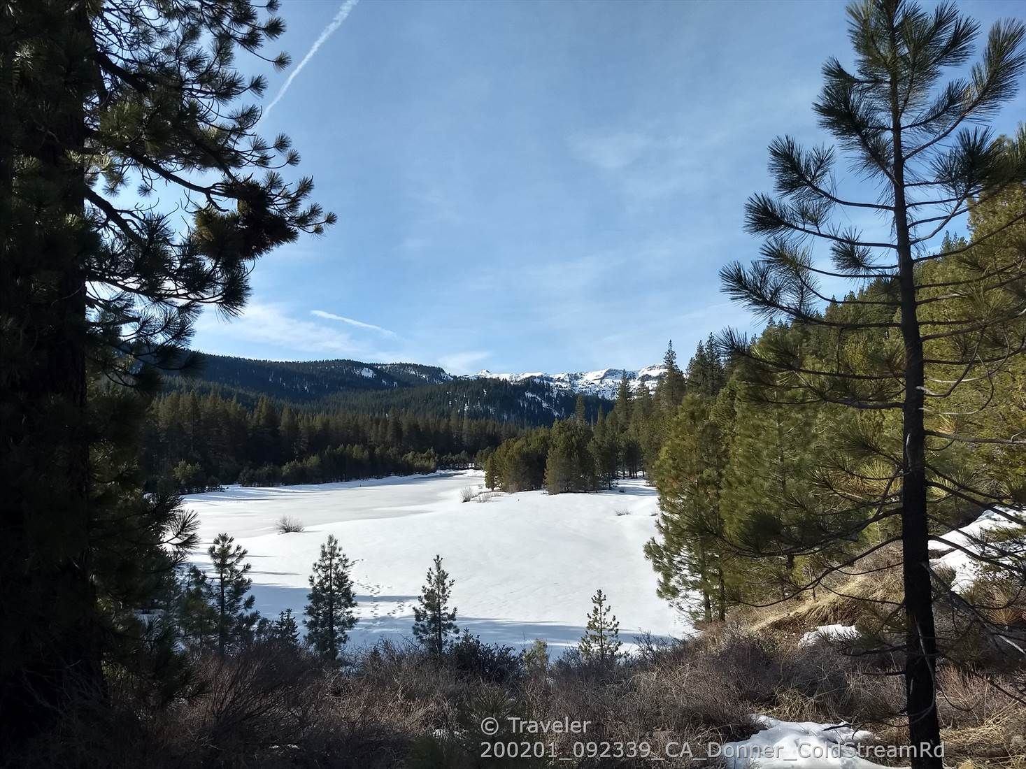 Frozen lake in a snowy valley, surrounded by pine trees and distant snow-capped mountains. - Cold Stream Valley loop