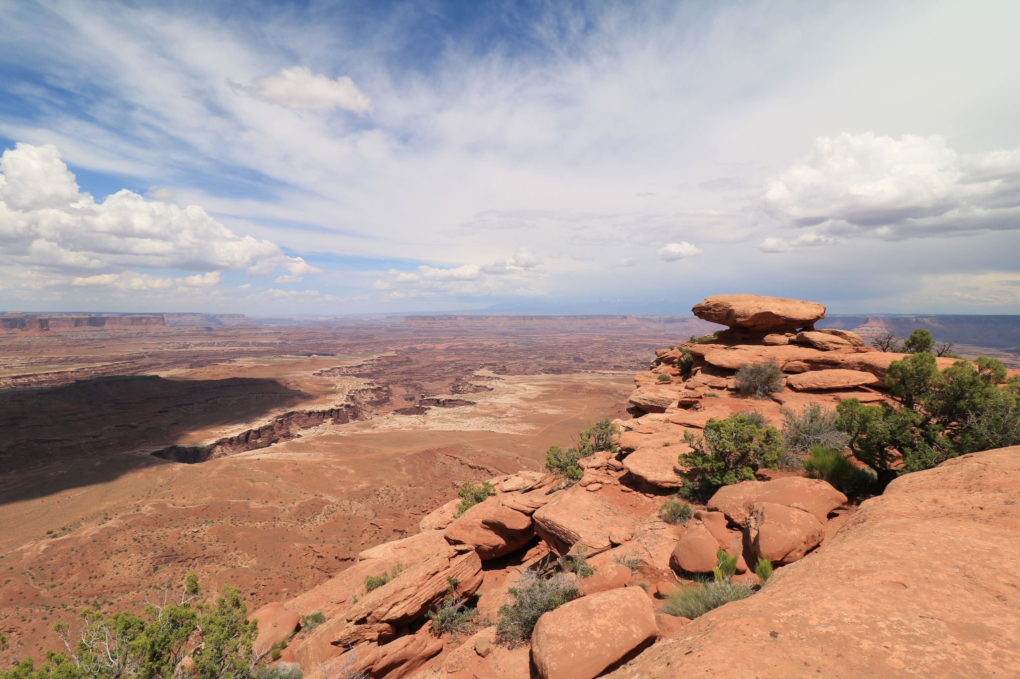 Expansive desert canyon view with red rock formations and a cloudy sky. - White Rim Overlook Trail