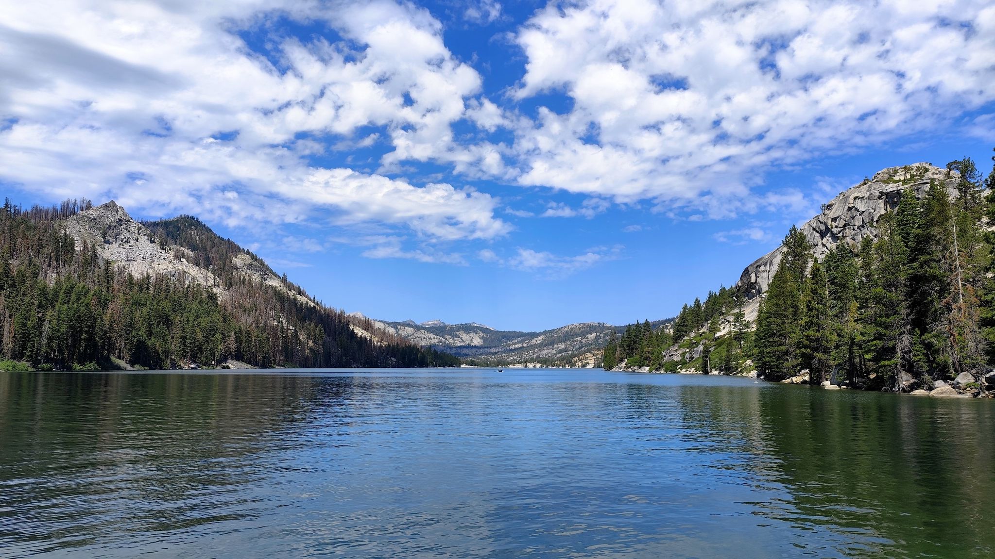 Lake between forested mountain slopes under a bright blue sky with clouds. - Echo Lake Ski Trail