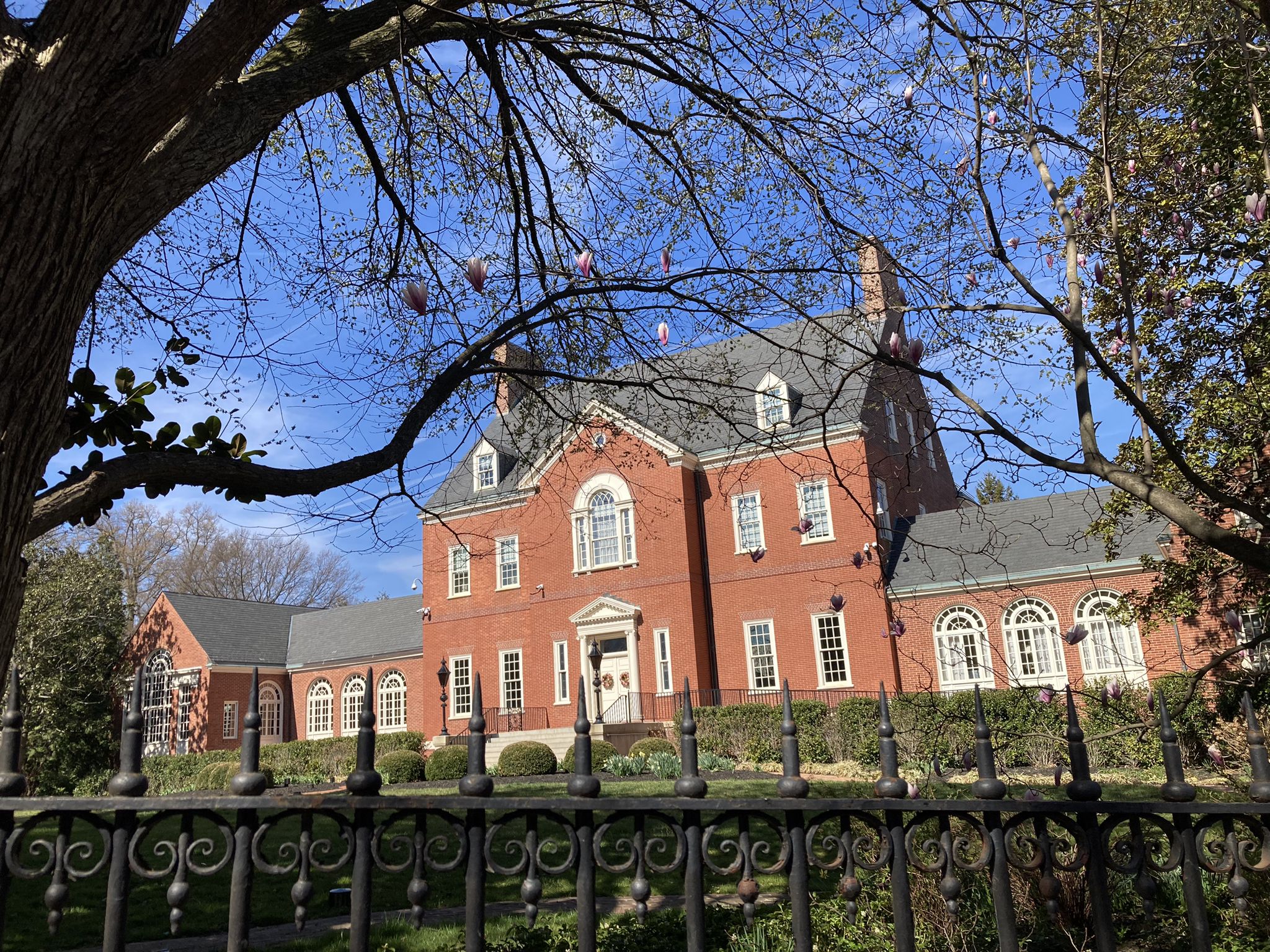 Large red brick mansion with white trim behind an ornate black fence. - Annapolis City Dock – Maryland State House loop from Annapolis