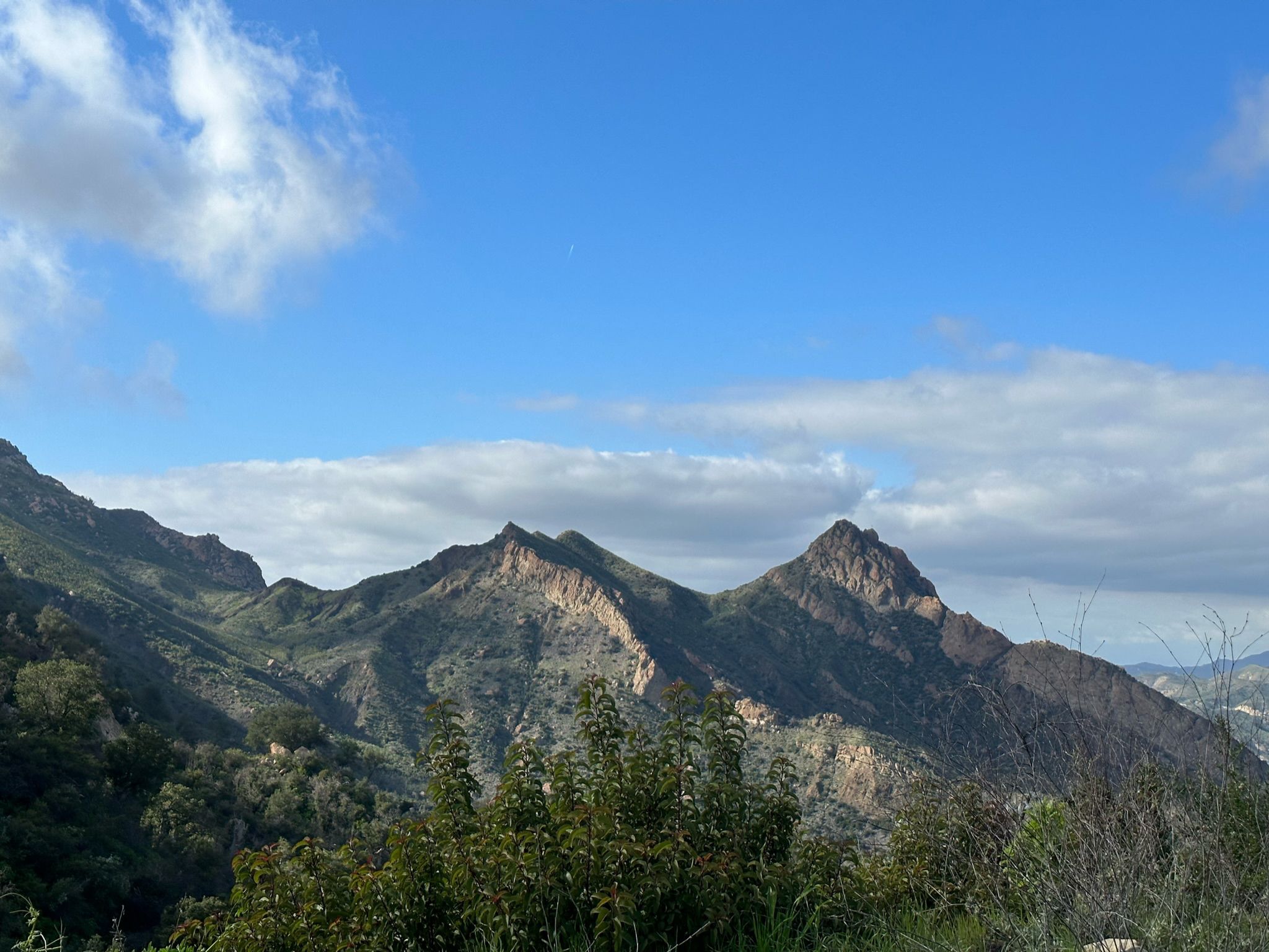 Rugged mountains under a bright blue sky with scattered white clouds. - Backbone Trail: Tapia to Kanan-Dume