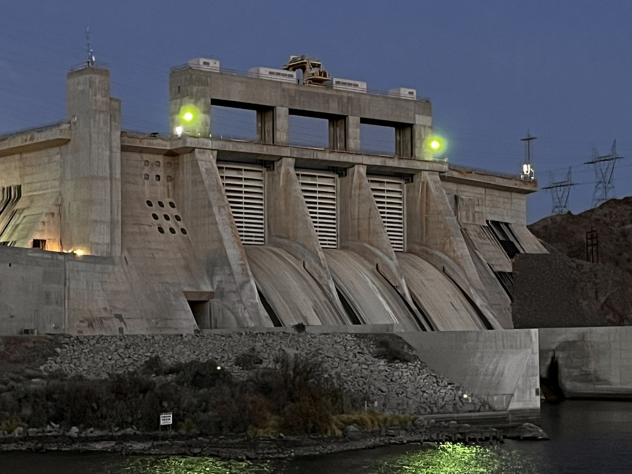 Concrete dam illuminated at dusk, with green lights reflecting on the dark water. - Pyramid Canyon Park Loop and Viewpoint