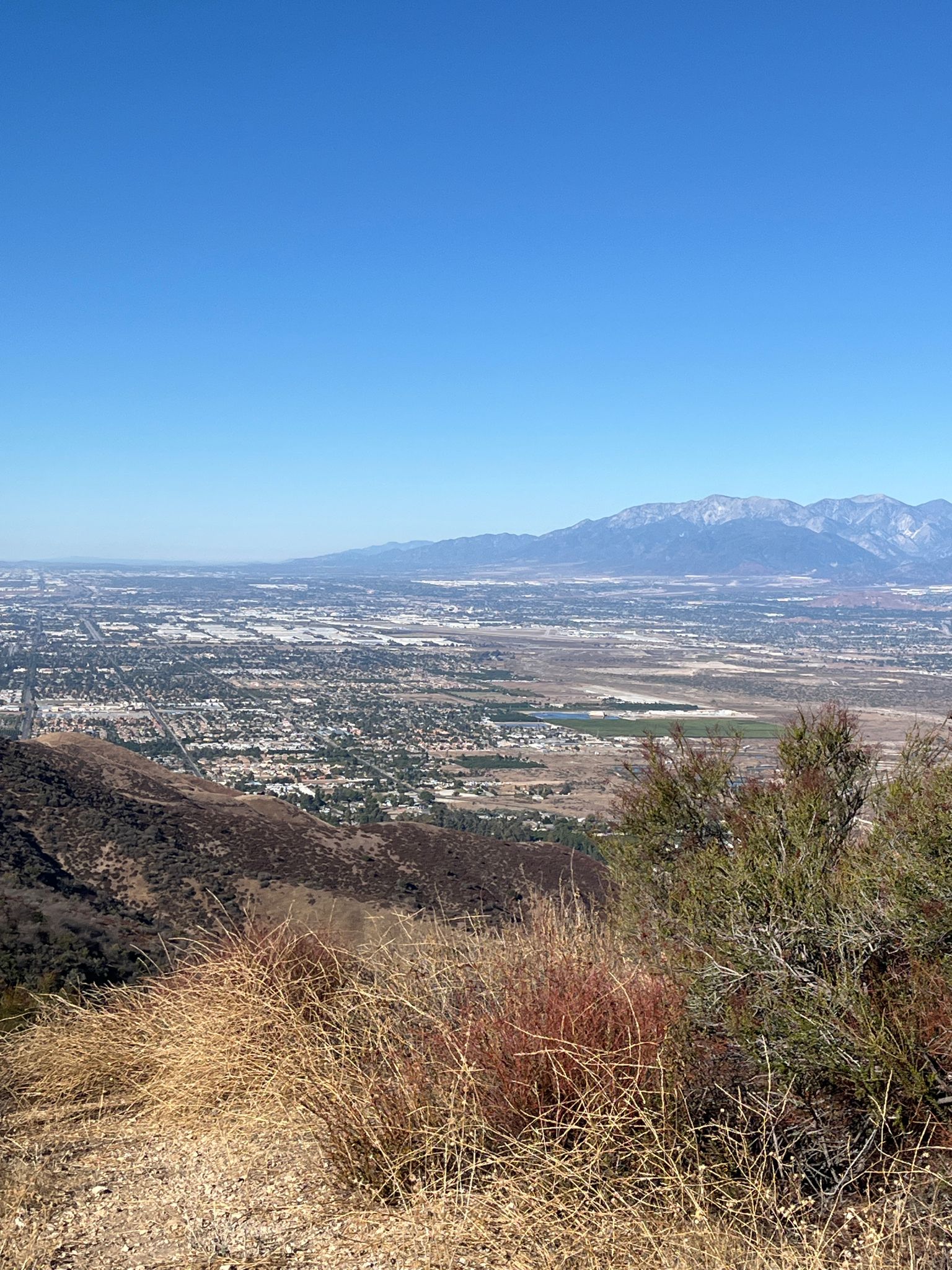 High-angle view of a city in a valley with distant snow-capped mountains. - Crafton Hills Loop
