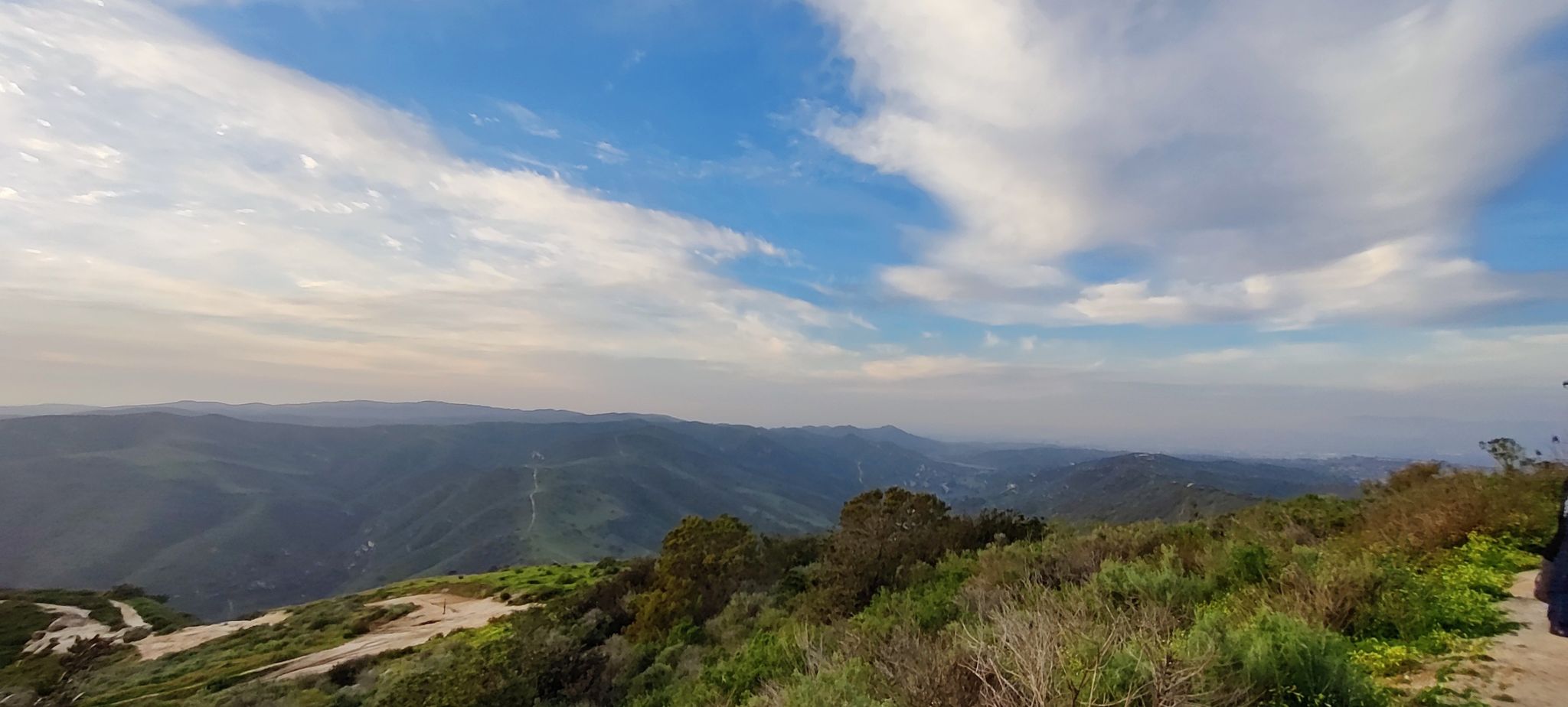 A panoramic view of green, rolling hills and valleys under a bright, cloudy sky. - Car Wreck Trail Loop