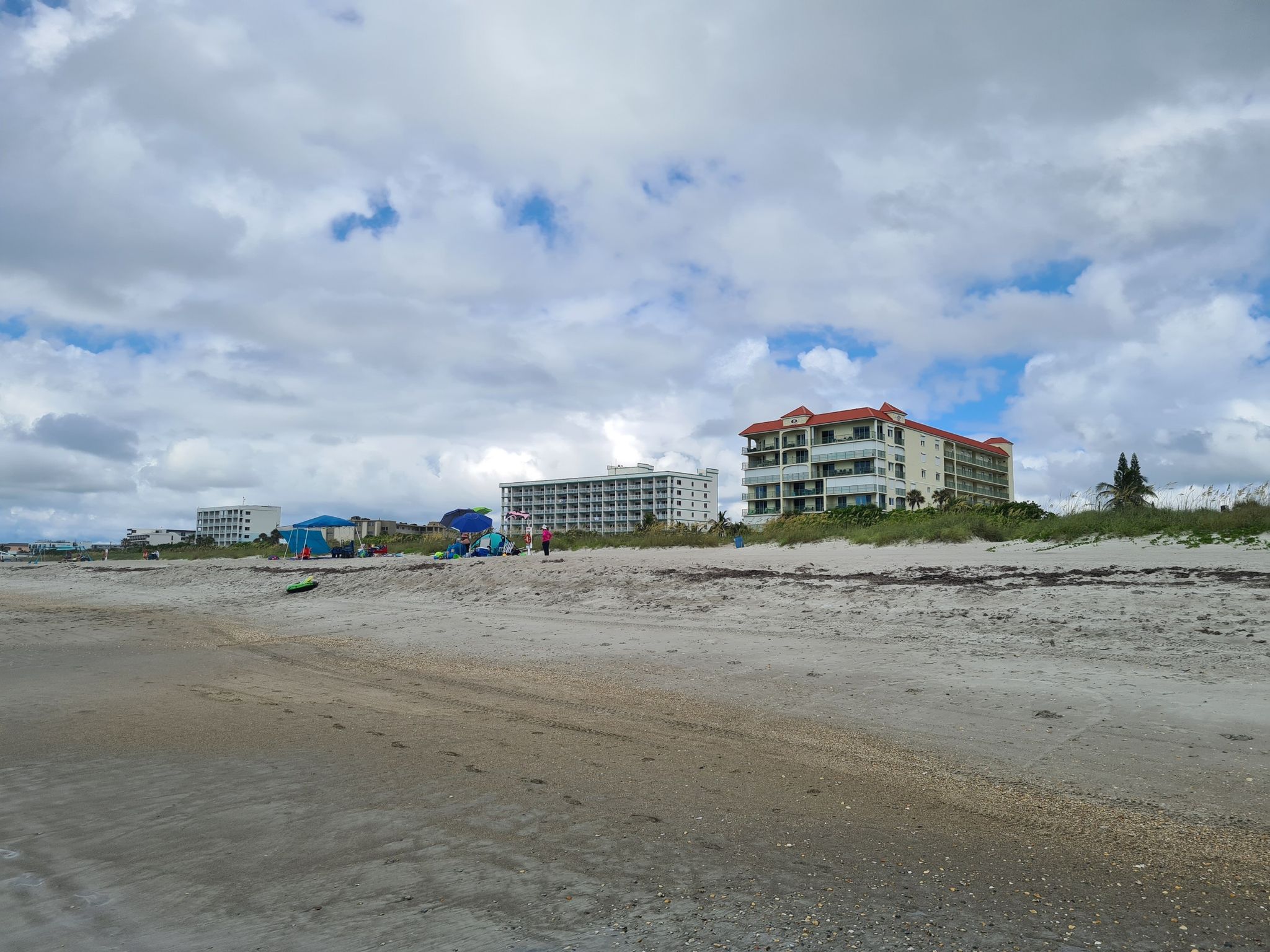 Wide sandy beach with distant buildings and a partly cloudy sky. - Cocoa Beach Pier loop from Four Islands